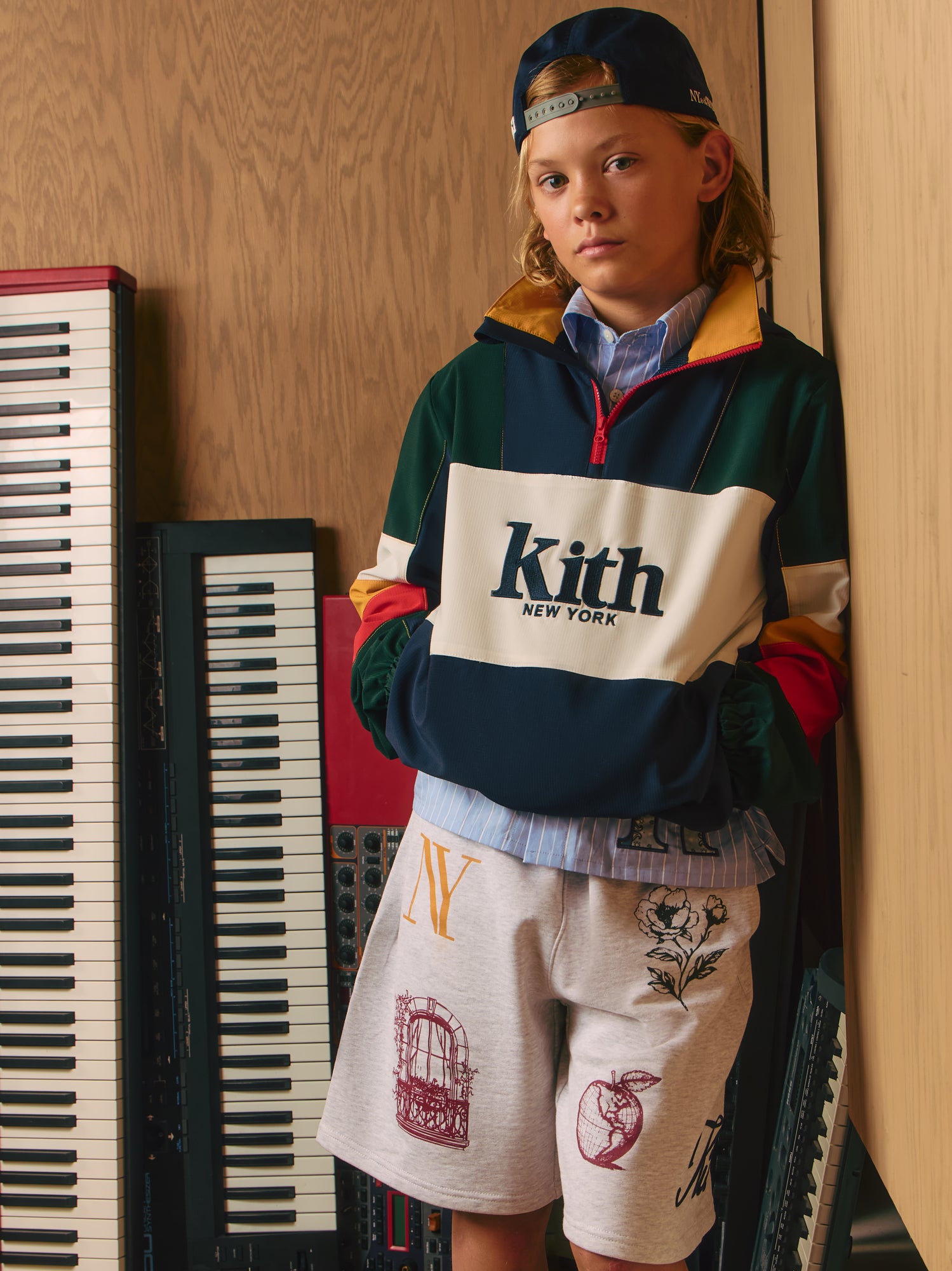Blond boy in Kith New York colorblock quarter-zip pullover and grey NY graphic sweat shorts by studio synthesizers