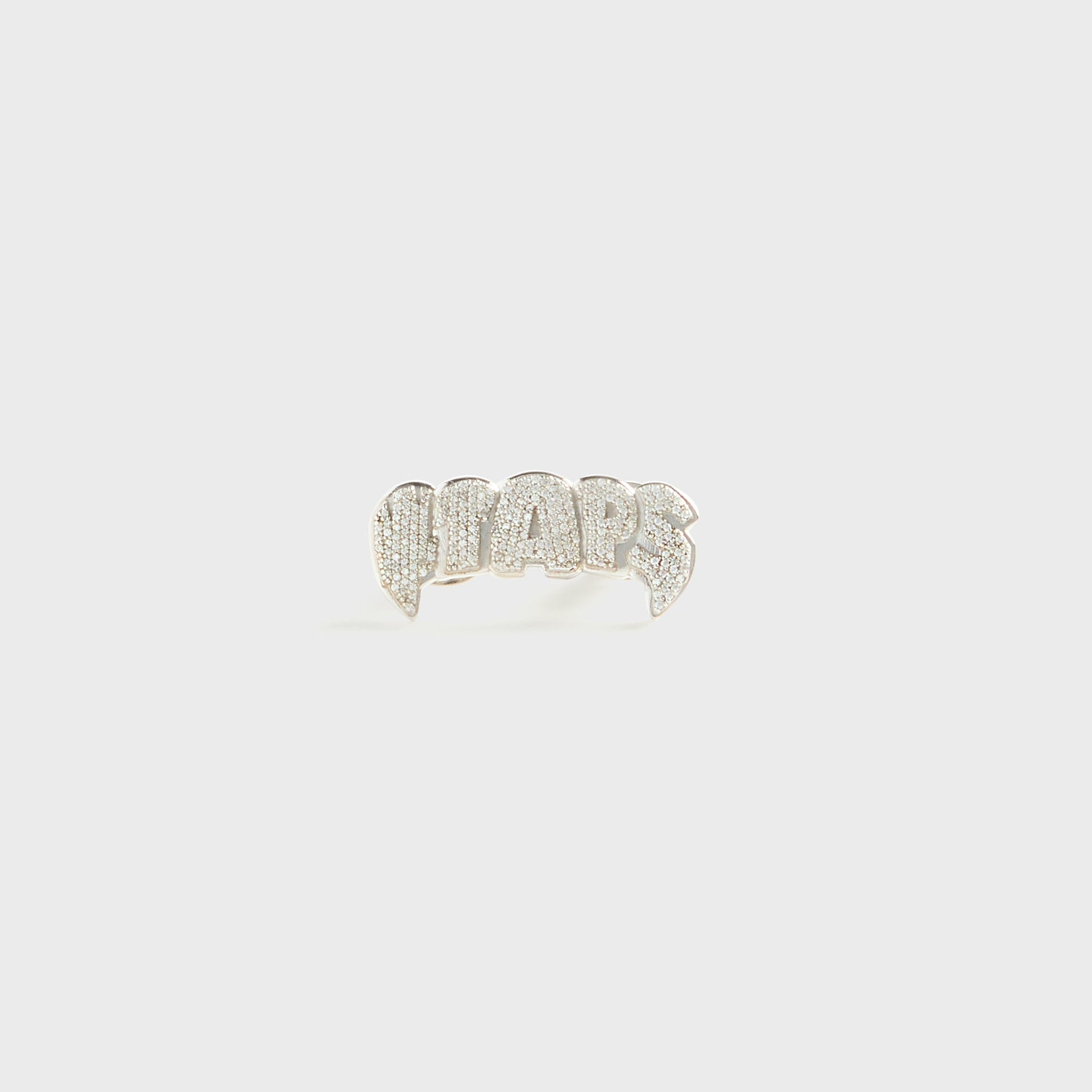 WTAPS x Grillz Jewelz Vamp badge in sterling silver, fanged grill-shaped pin with pave-set crystal WTAPS lettering, front view