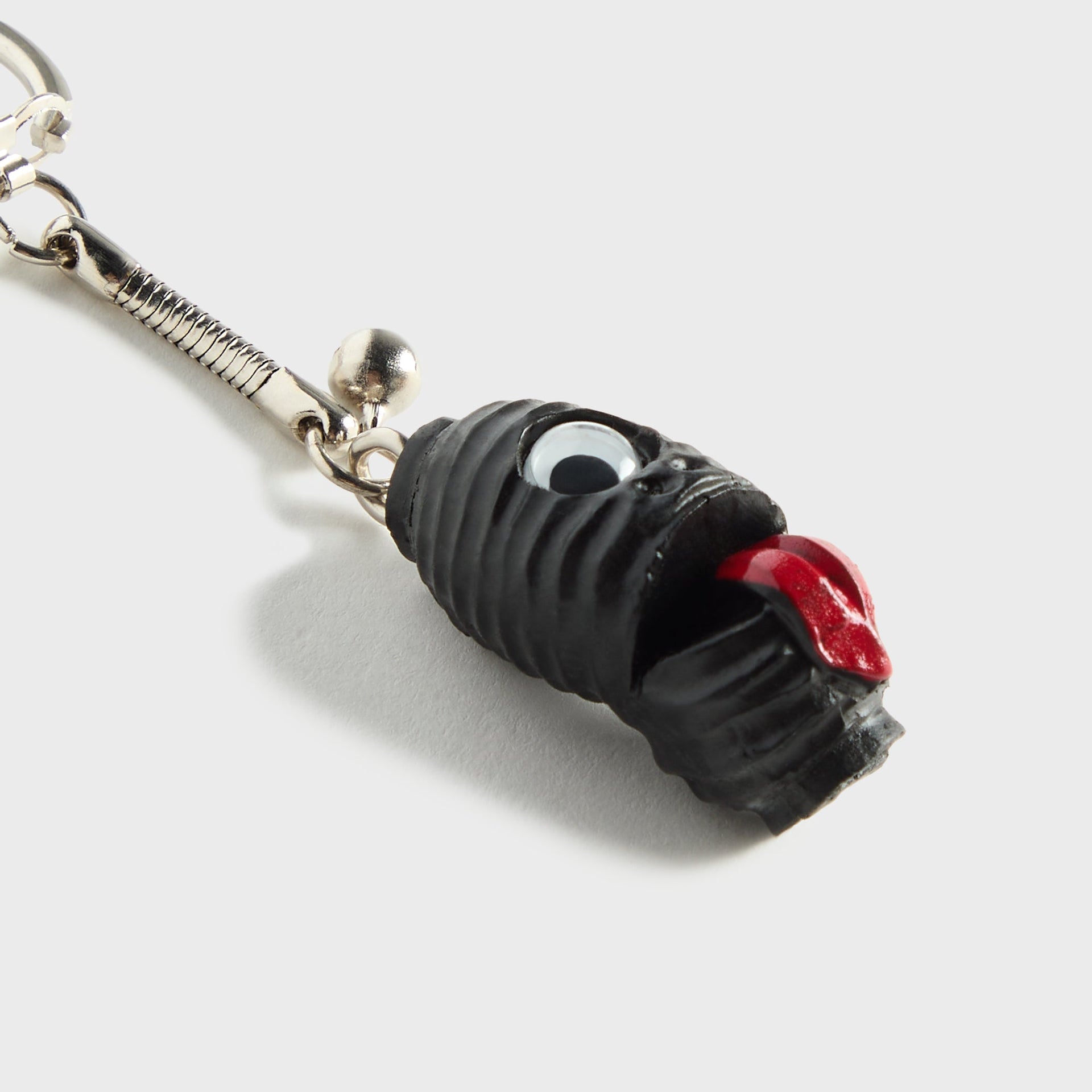 WTAPS x Masa Sculp Bonanza black resin key chain, close-up detail of textured creature charm with googly eye and red tongue