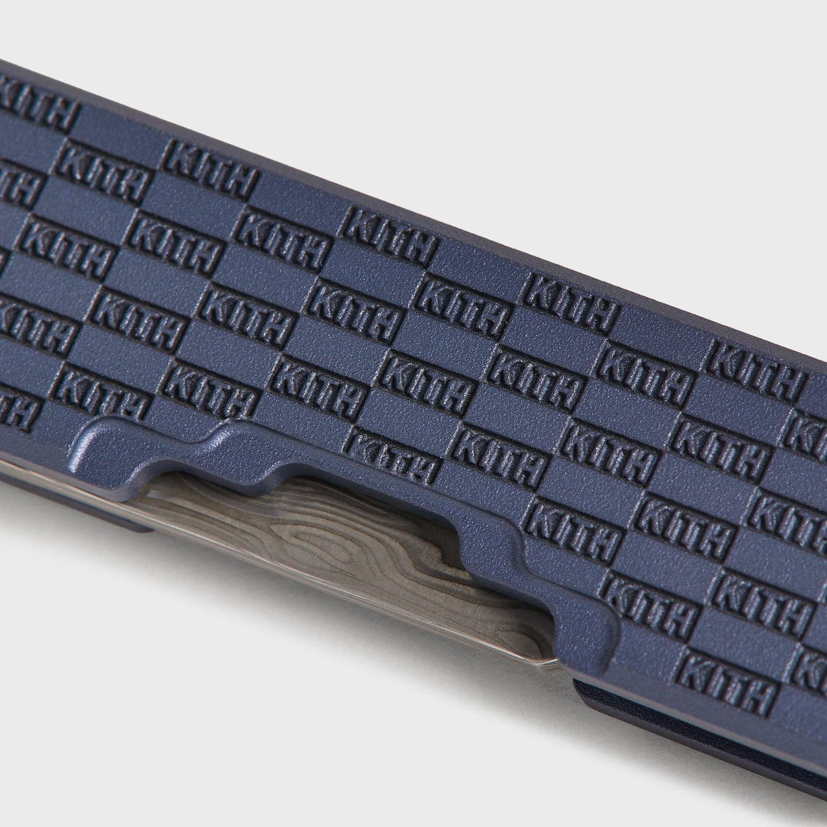 Close-up of the Kith x Benchmade Yamori Nocturnal knife's spine, etched kanji lettering beside the KITH checker pattern