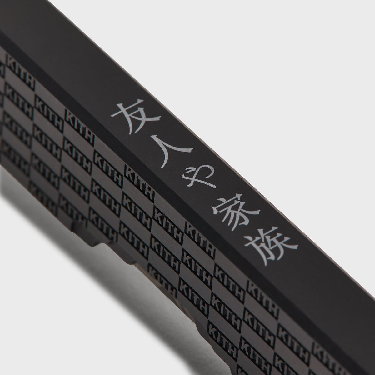 Macro detail of the KITH checkerboard engraving on the Kith x Benchmade Yamori Black knife's titanium handle