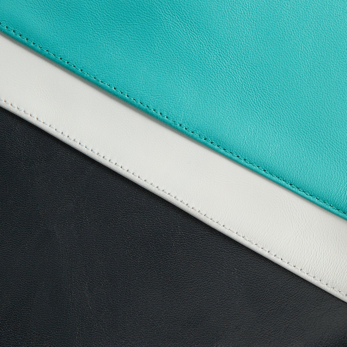 Close-up of teal, cream and black leather panel stitching on the Kith & AVIREX Vancouver Grizzlies jacket