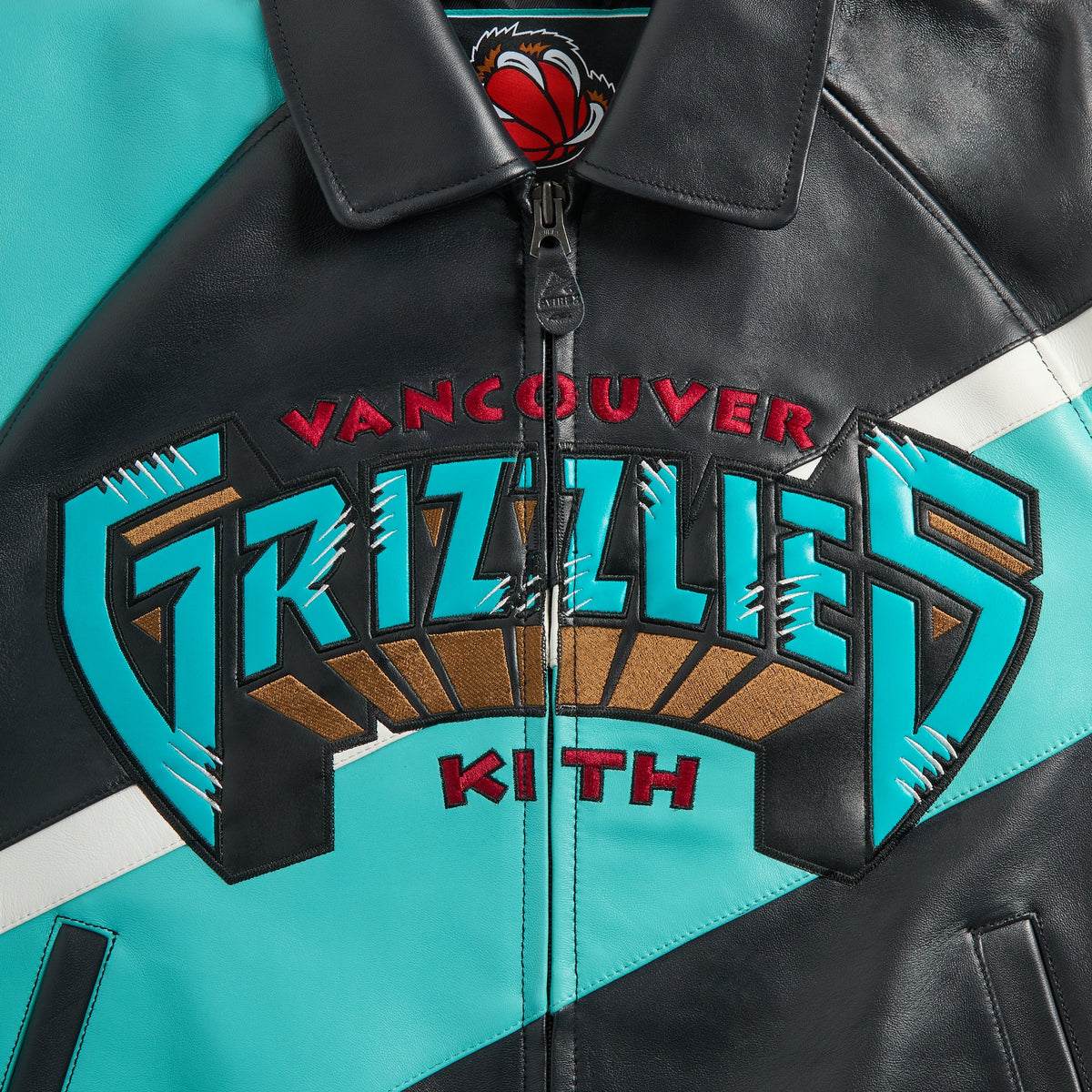 Close-up of Vancouver Grizzlies Kith chest embroidery and zip collar on the teal and black Kith & AVIREX leather jacket