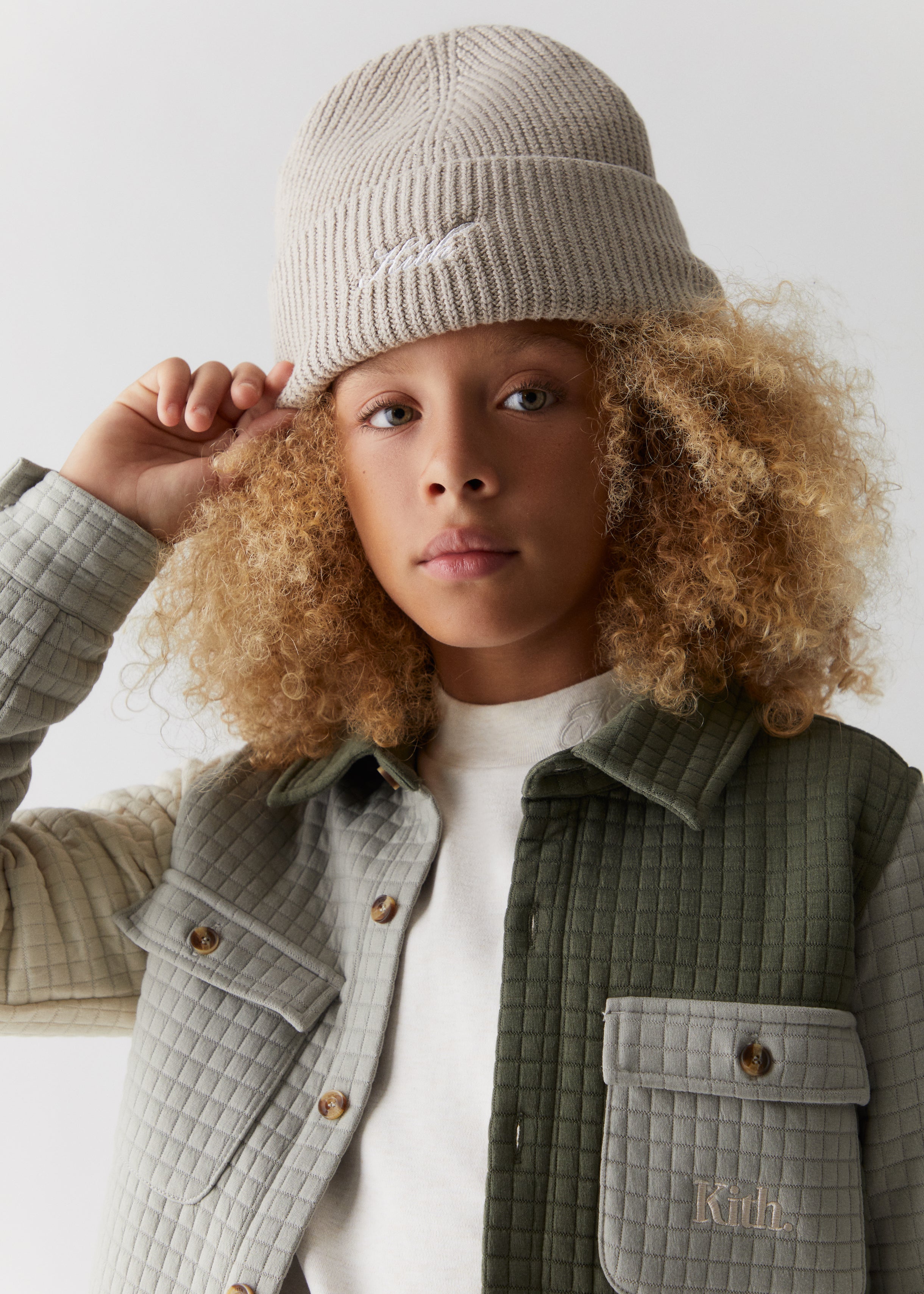 A child wearing a Kith script knit beanie and quilted color-blocked shacket.