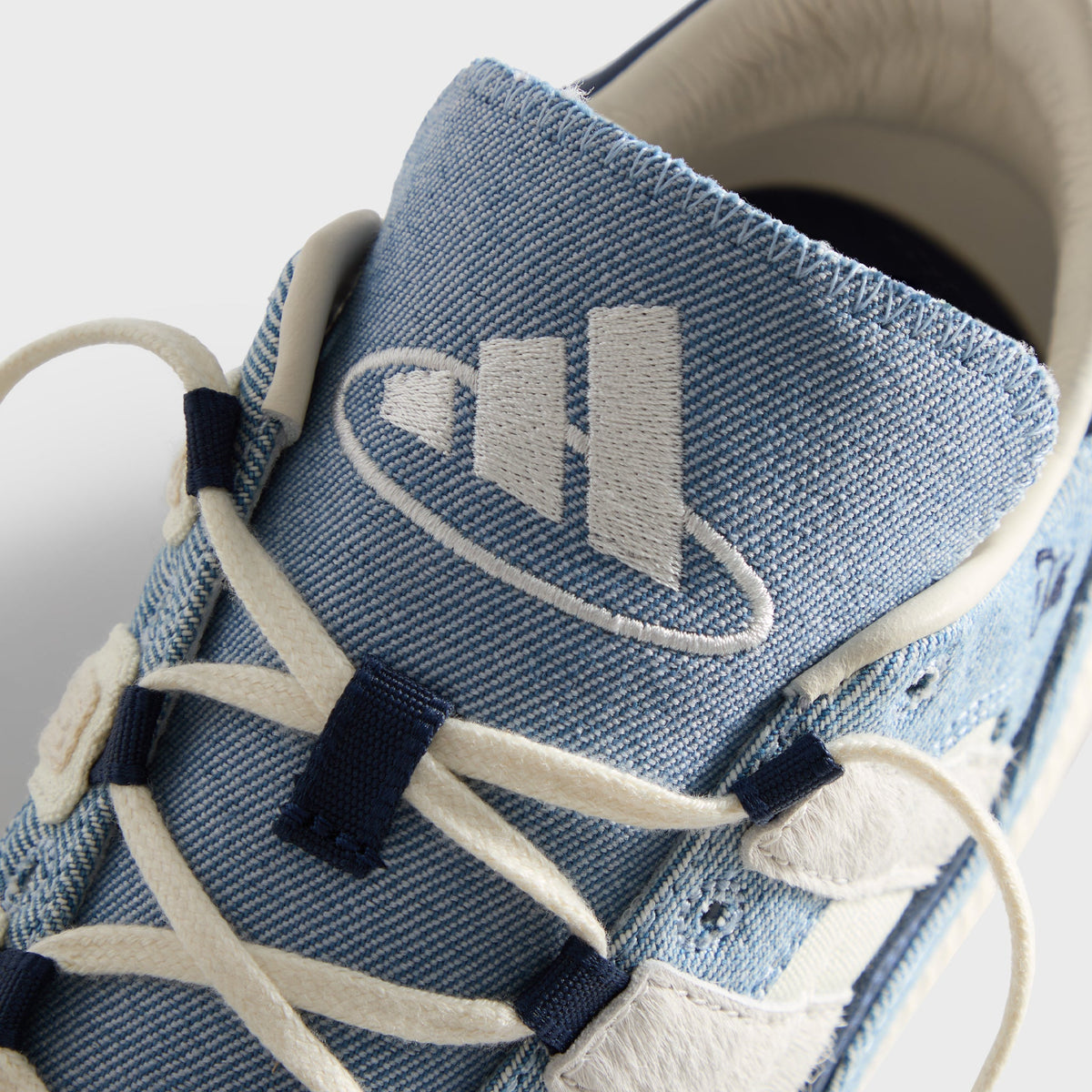 Kith for adidas Football Supernova Indoor in Denim/Gum, top-down close-up of the tongue with adidas Badge of Sport on denim