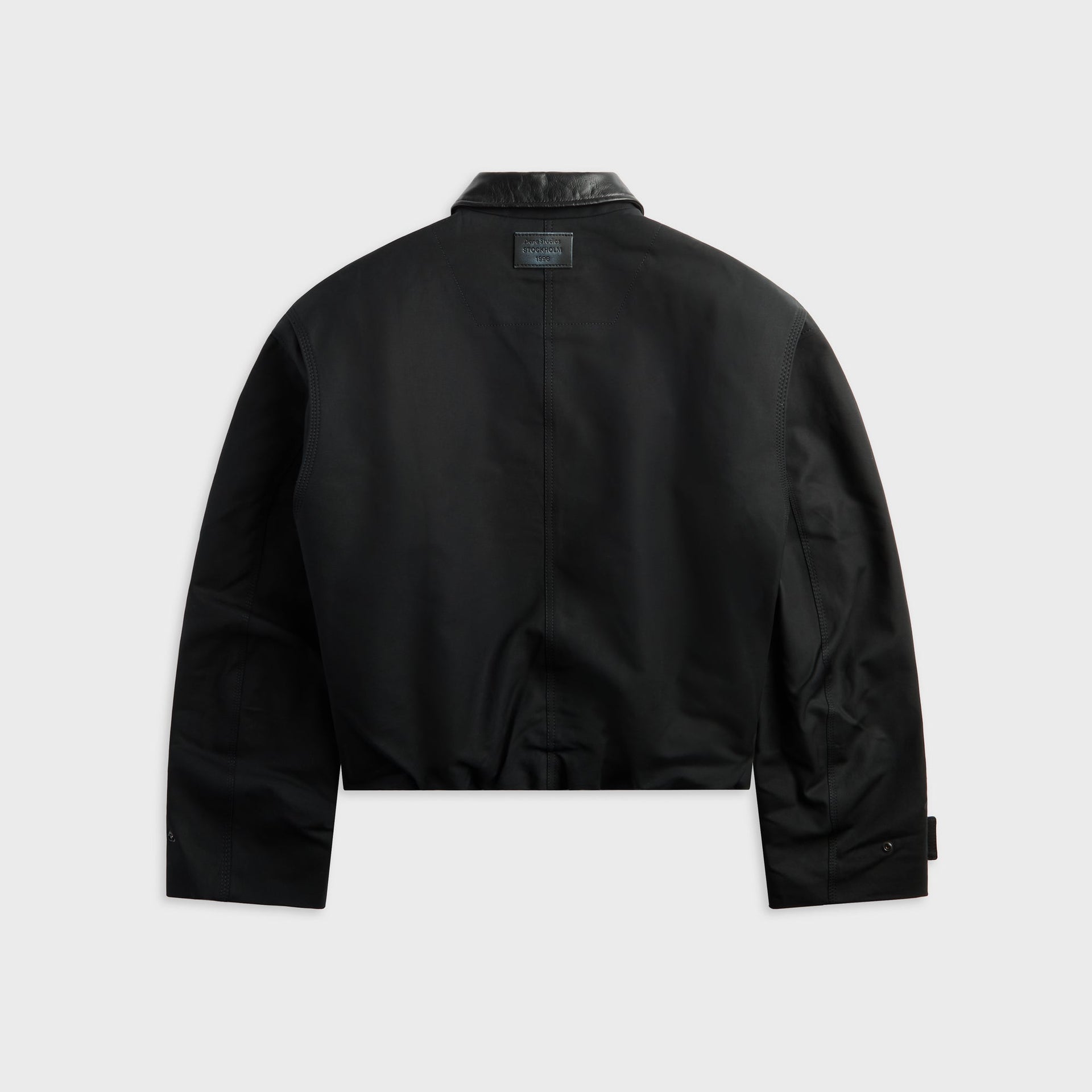 Acne Studios black bomber jacket with leather collar, back view showing Stockholm 1996 leather patch, flat lay