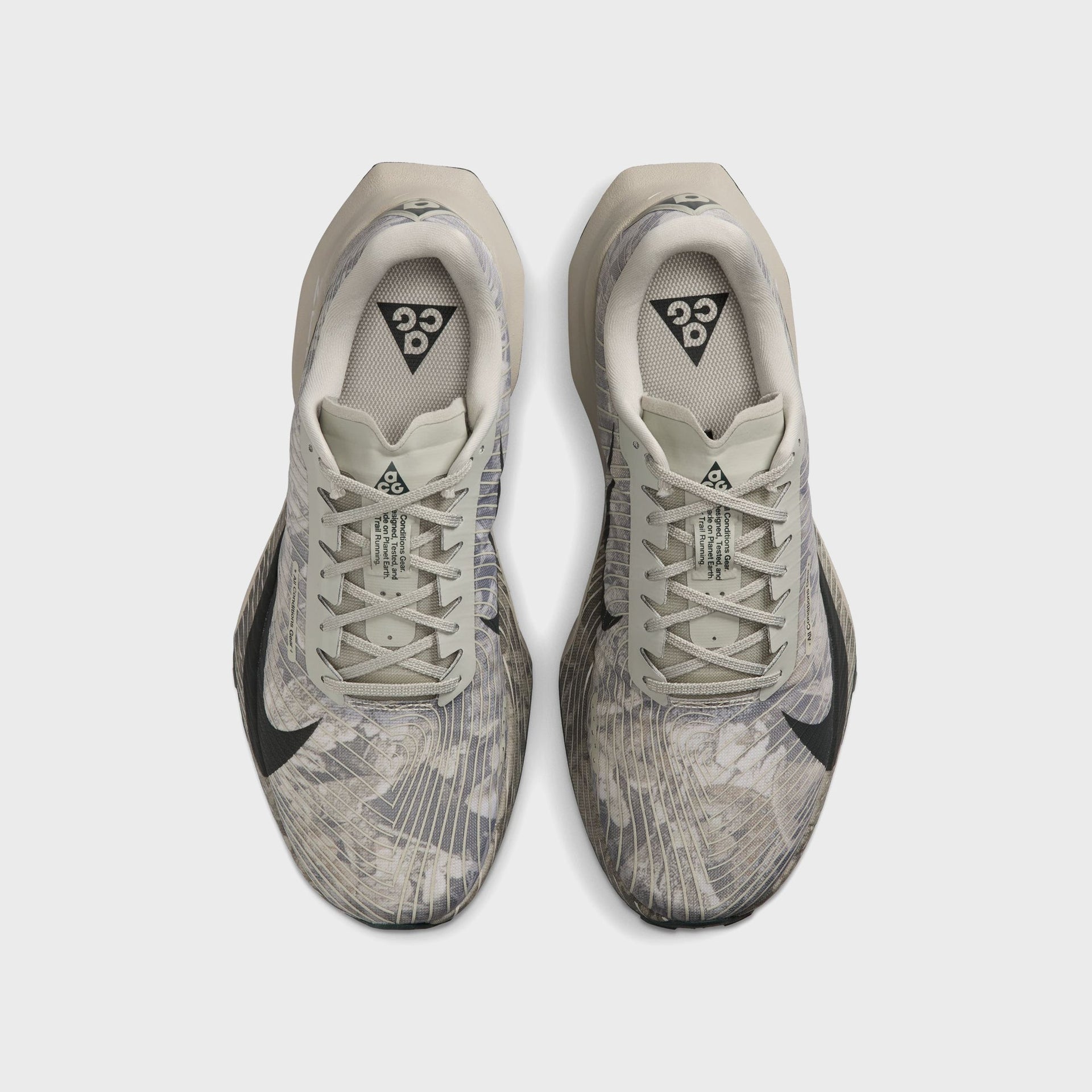Pair of Nike ACG Ultrafly Trail running shoes, top-down view with ACG triangle tongue tags and crossed grey laces