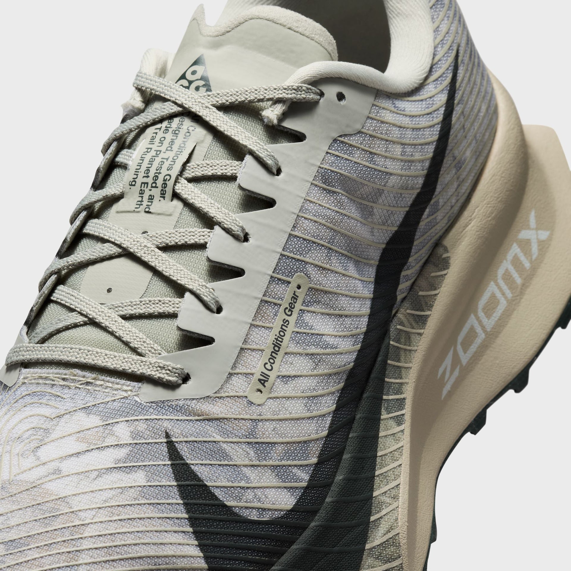 Close-up of a Nike ACG Ultrafly Trail running shoe showing crossed laces, ACG hangtag and ZoomX foam sidewall text