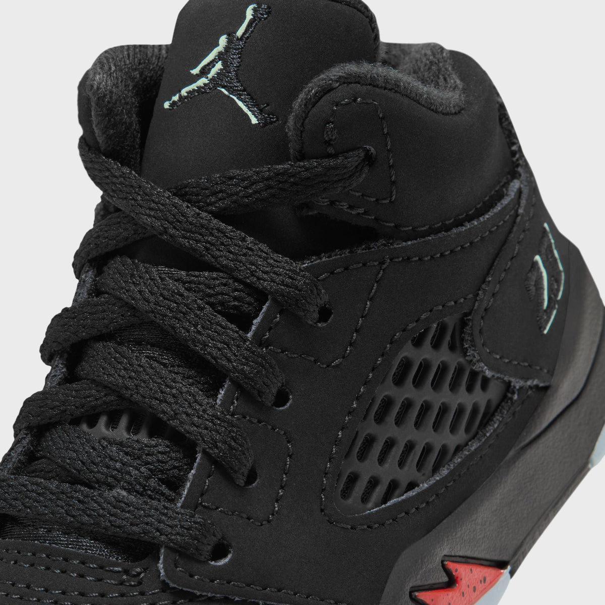 Close-up of Jordan TD Jordan 5 Retro laces, mint Jumpman logo and mesh panel on black nubuck