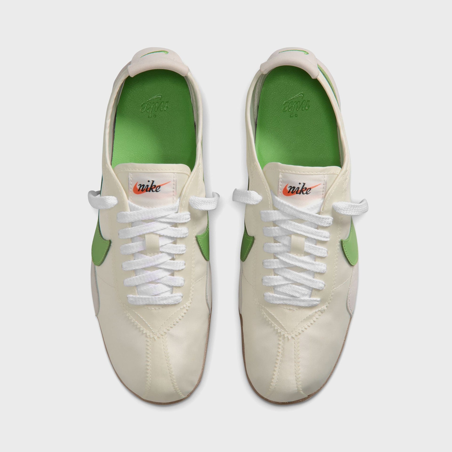 Nike WMNS Moon Shoe overhead top-down view of the pair showing green insoles and orange 'nike' script tongue tags
