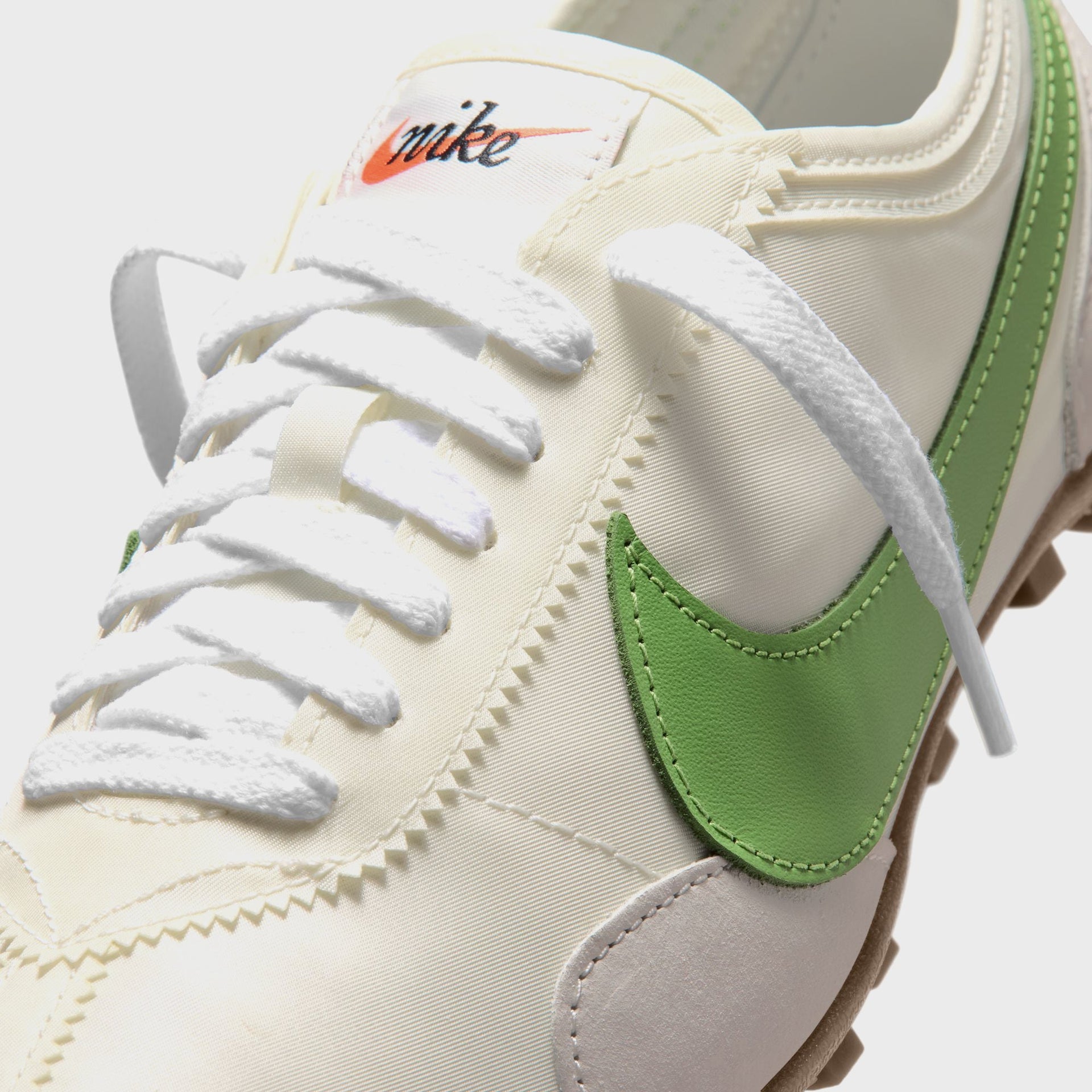 Nike WMNS Moon Shoe close-up of the toe with white laces, green leather Swoosh and orange 'nike' script tongue label