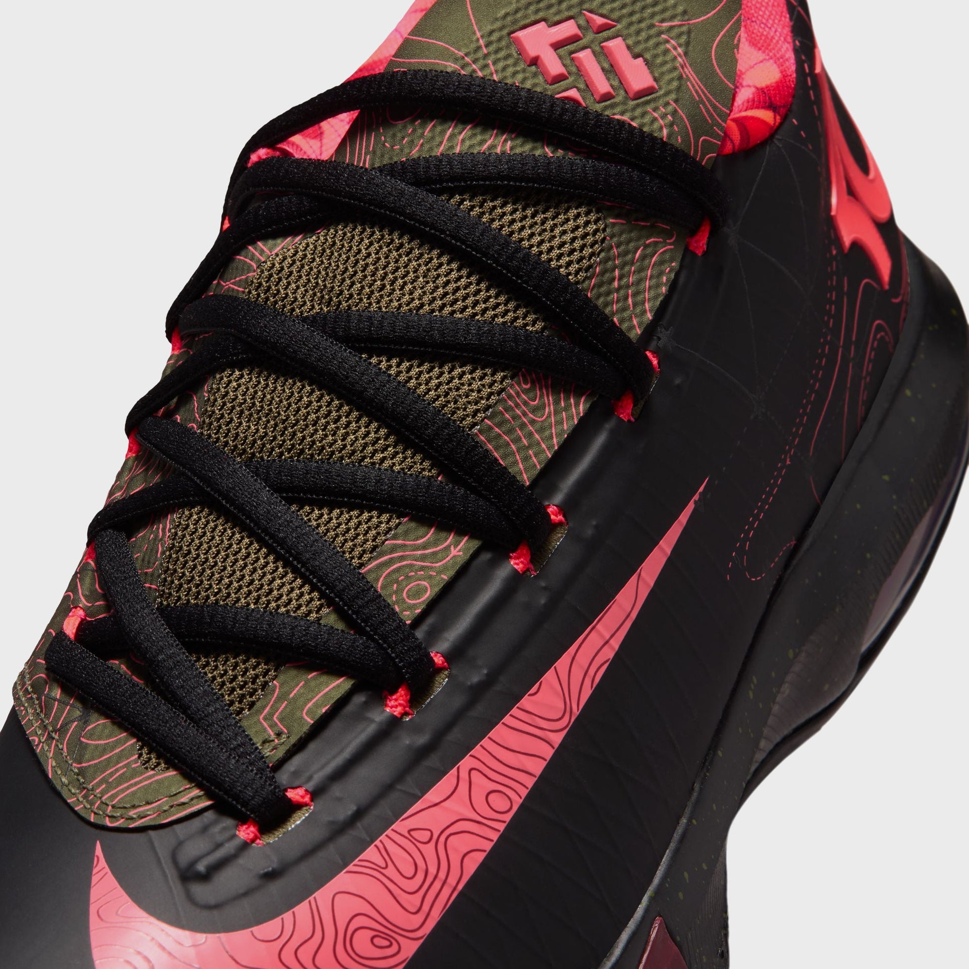 Close-up of a Nike KD 6 basketball shoe showing crossed black laces, olive topographic tongue and red swoosh