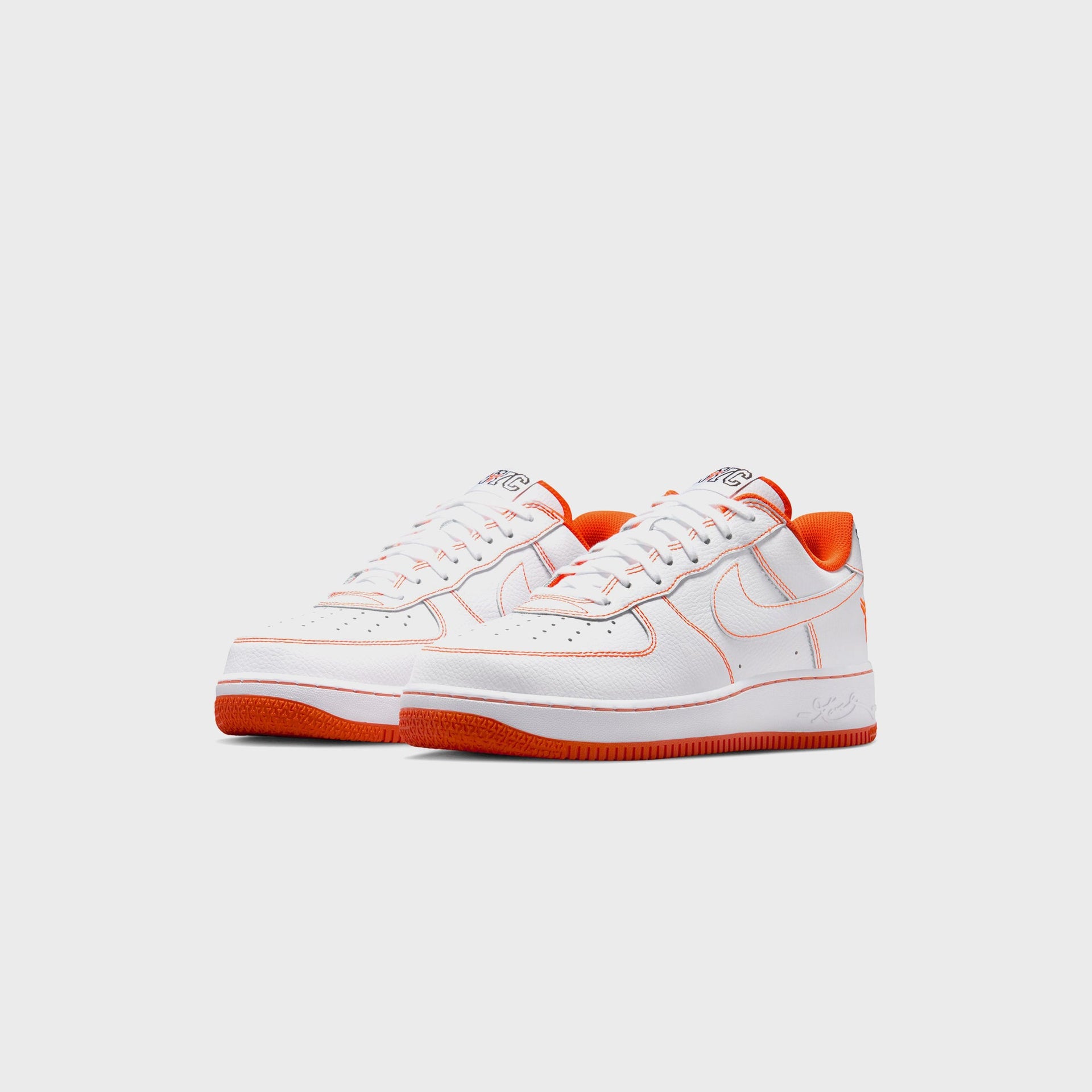 Nike Air Force 1 Low Protro NYC pair angled from the front, white leather with orange contrast stitching, NYC tongues and orange soles