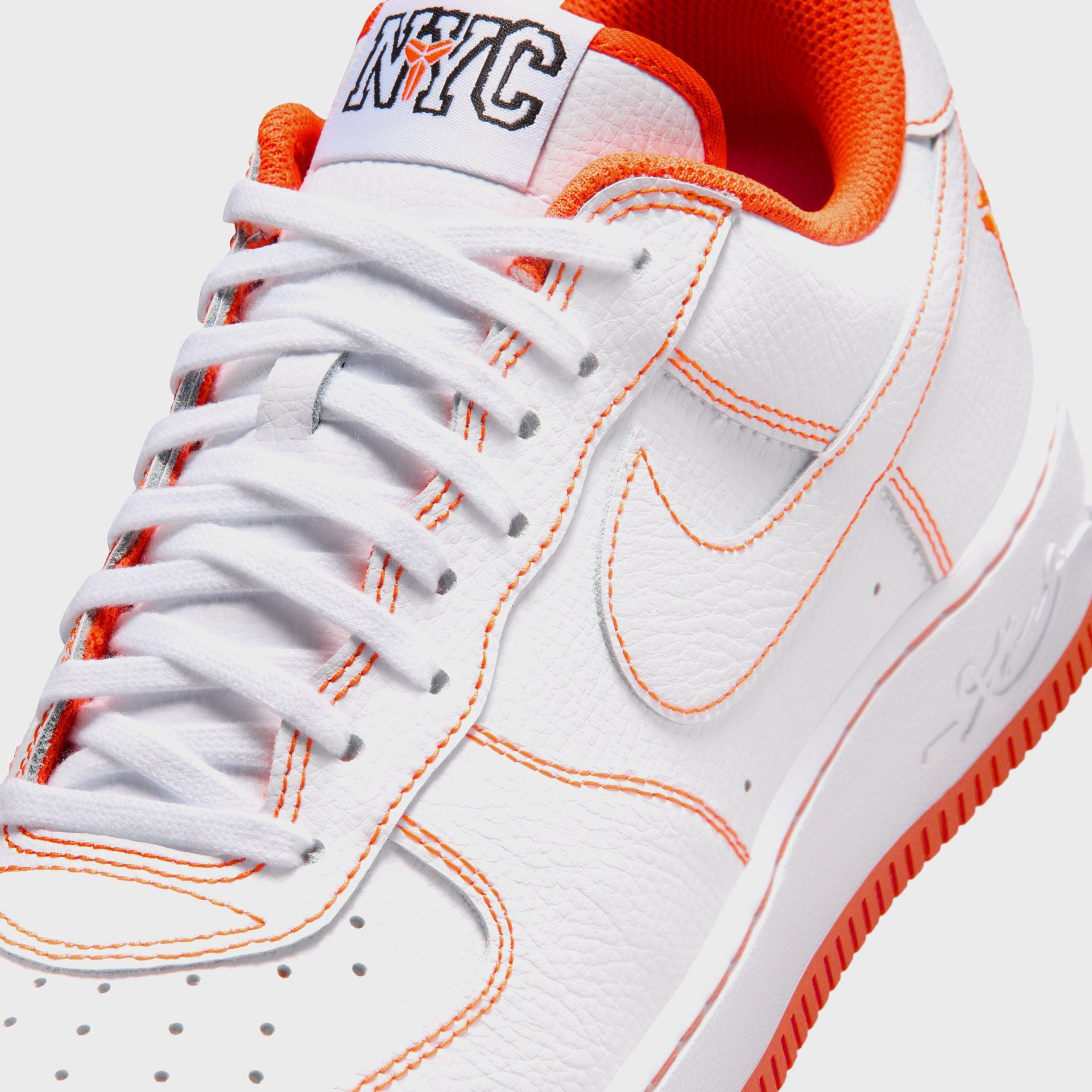 Close-up of the Nike AF1 Low Protro NYC toe and laces with orange contrast stitching, white Swoosh and NYC tongue tag