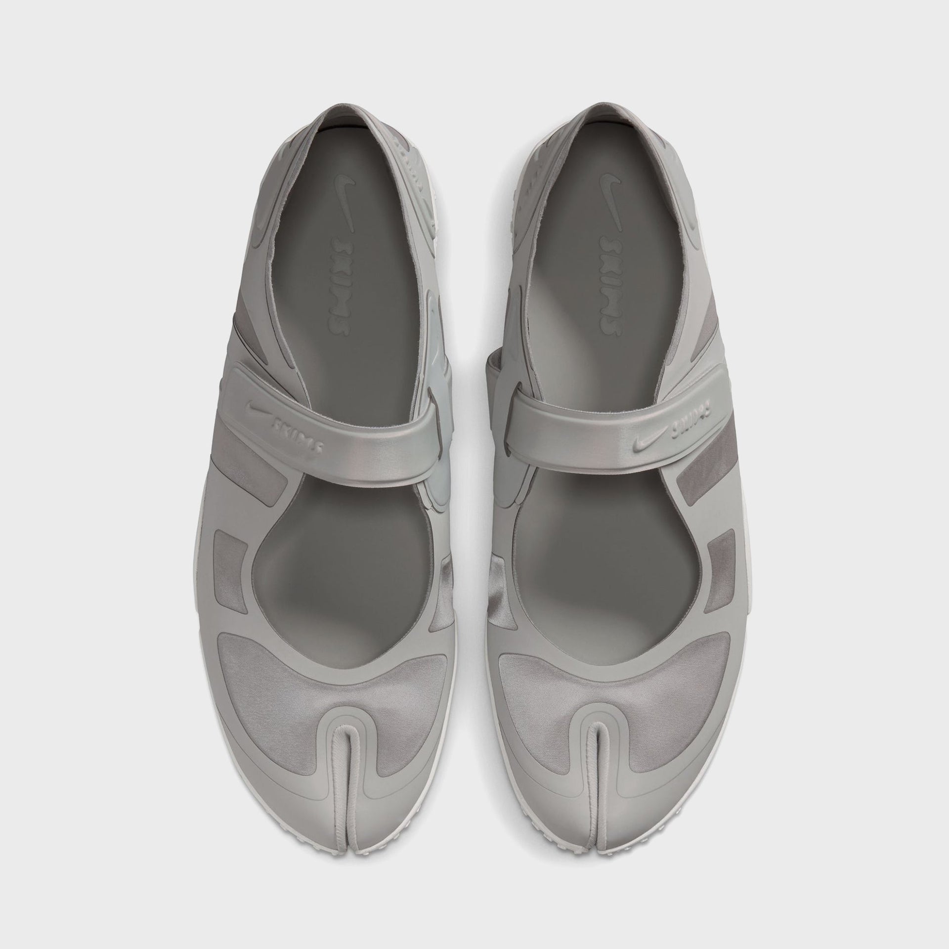 NikeSKIMS Rift Satin sneakers viewed top-down, pair showing Nike Swoosh and SKIMS-branded hook-and-loop straps over split-toe uppers
