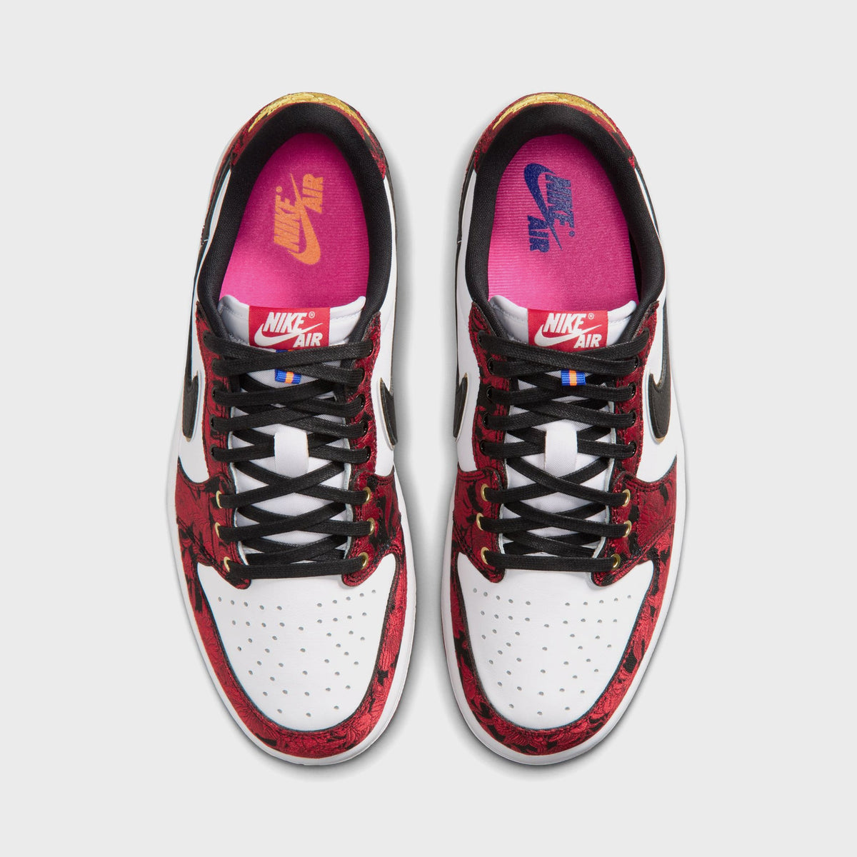 Top-down view of Air Jordan 1 Low OG pair showing pink Nike Air insoles, black laces, and red floral-embroidered toe box and eyestay