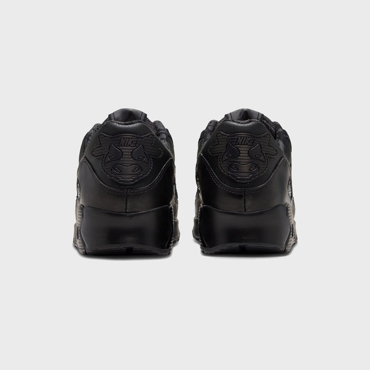 Heel view of Nike x Wagyu Air Max 90 pair with embossed cattle-head graphic and Nike wordmark