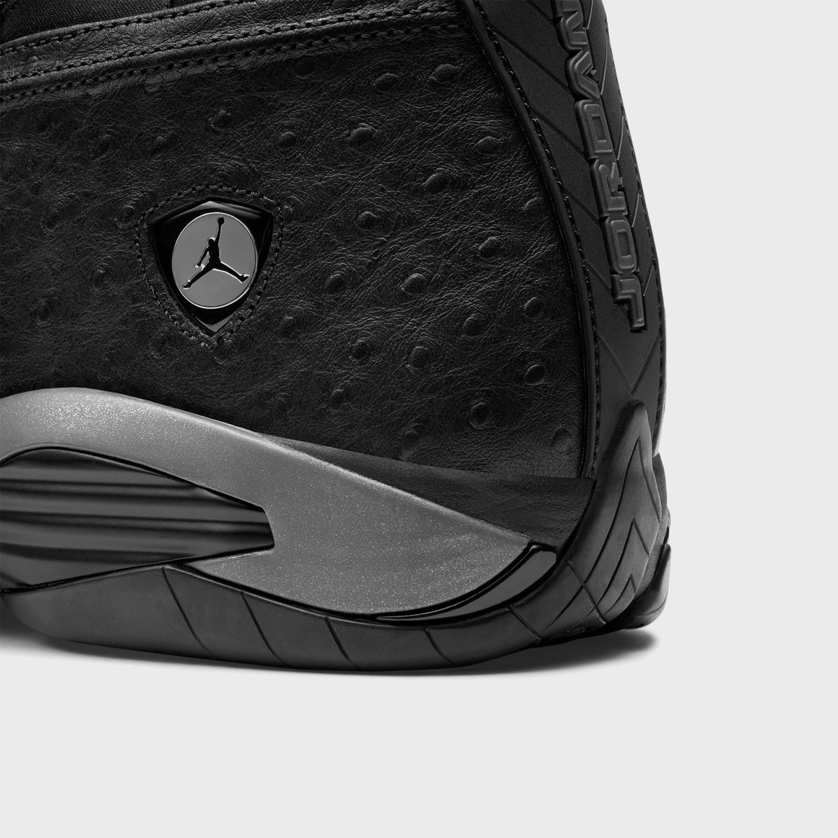 Close-up of Air Jordan 14 Low heel in black ostrich-textured leather with Jumpman shield badge and grey outsole