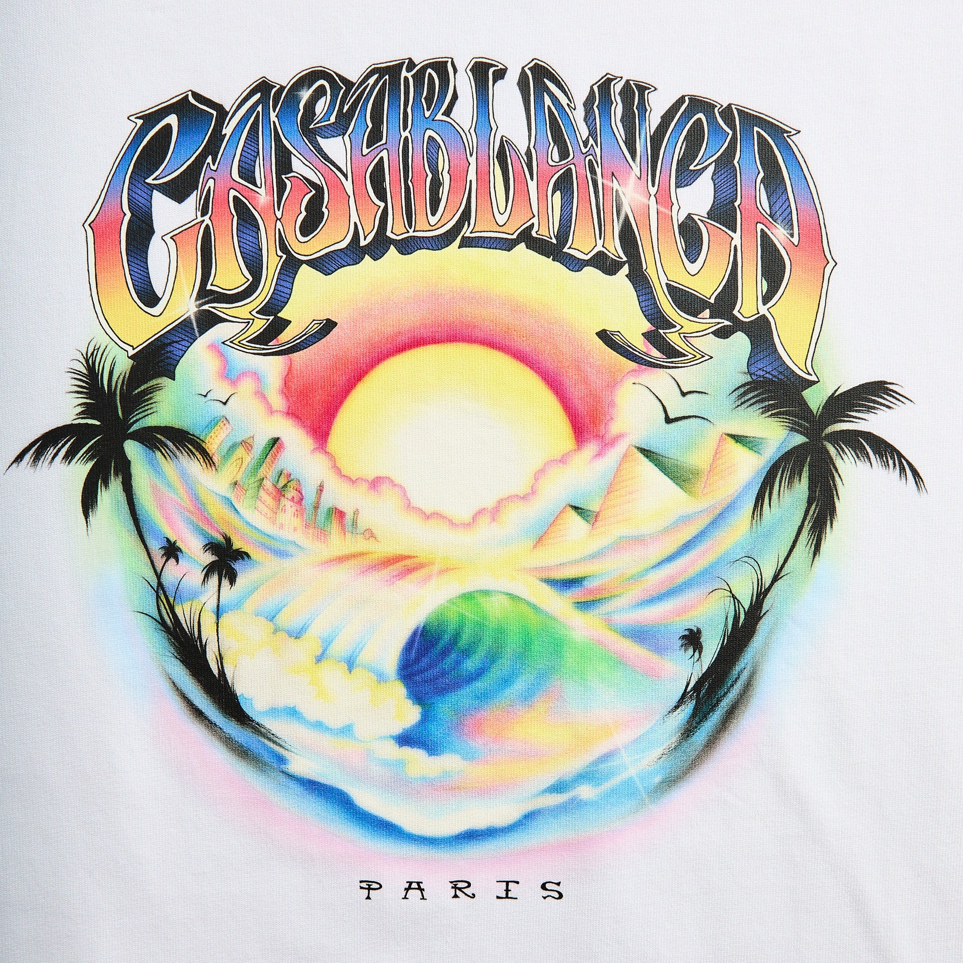 Close-up of Casablanca Casa Airspray graphic: airbrushed rainbow Casablanca logo over a sunset with palms, ocean wave and pyramids