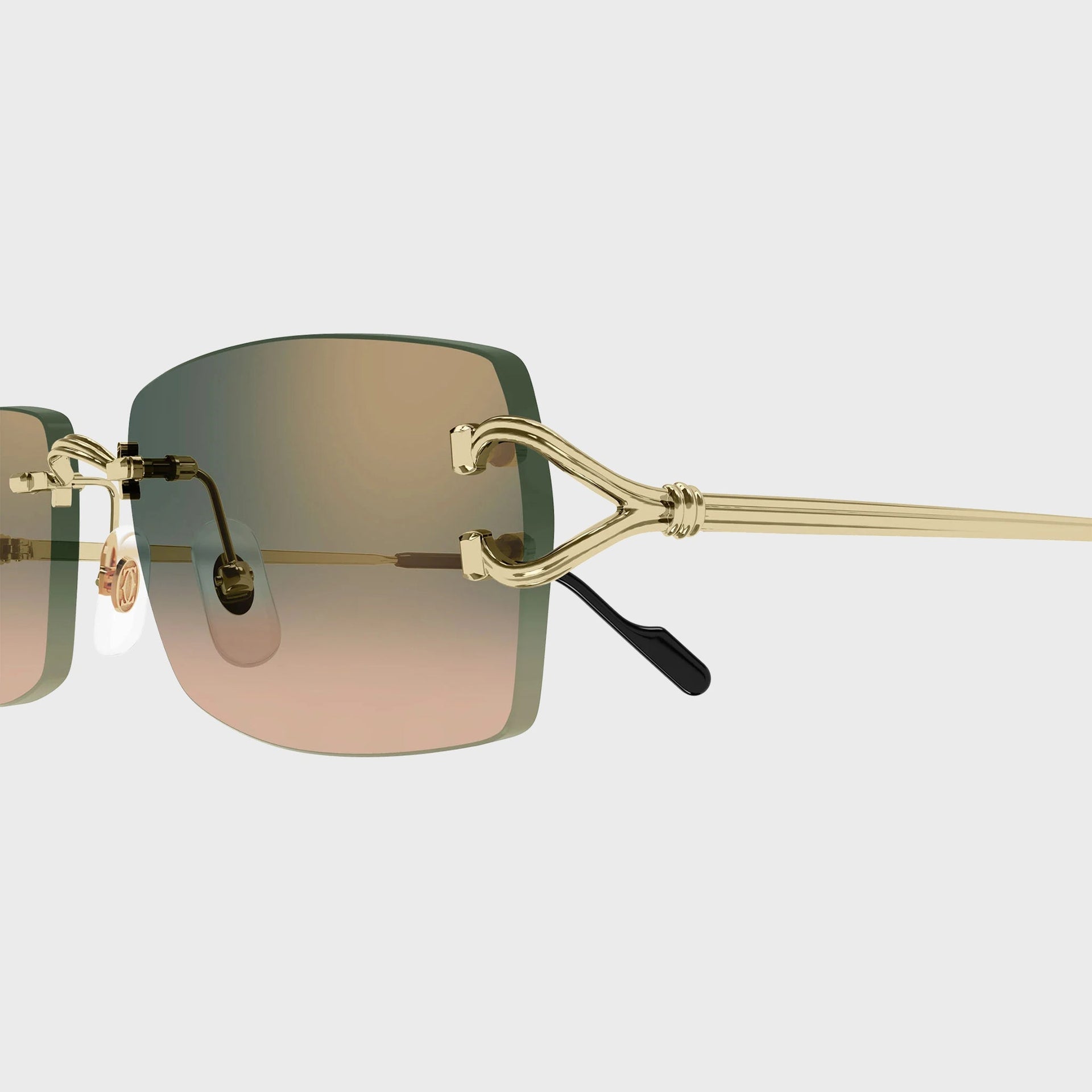 Close-up of the gold C-shaped temple hinge and green-peach gradient lens on Cartier Decor C sunglasses