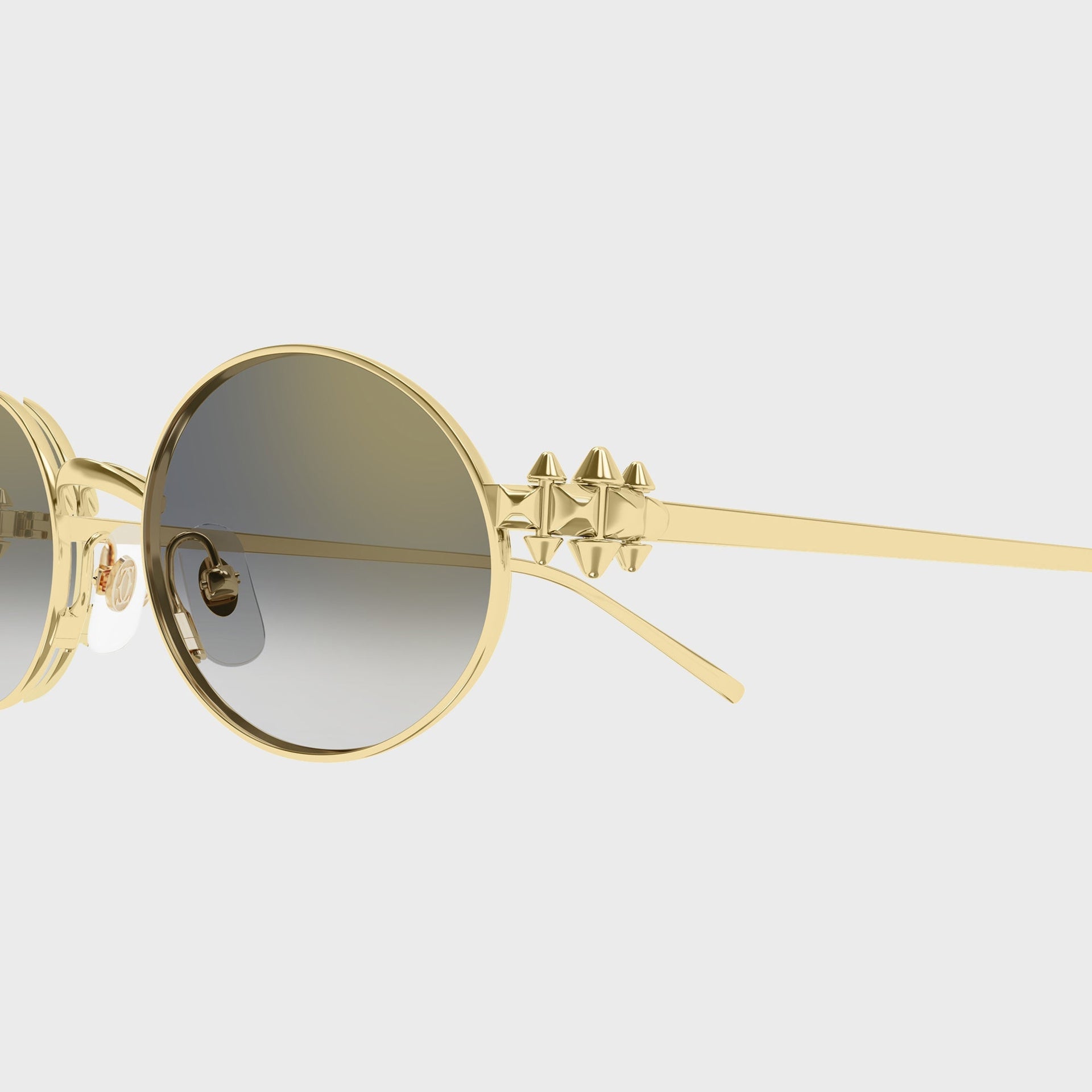 Close-up of the gold pyramid-stud temple hinge and grey gradient lens on Cartier CT0644S oval sunglasses