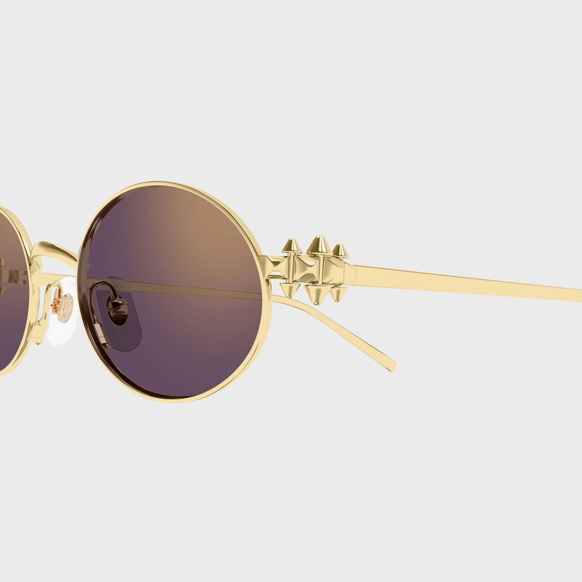 Close-up of the gold pyramid-stud temple hinge and violet-brown lens on Cartier Clash CT0644S sunglasses
