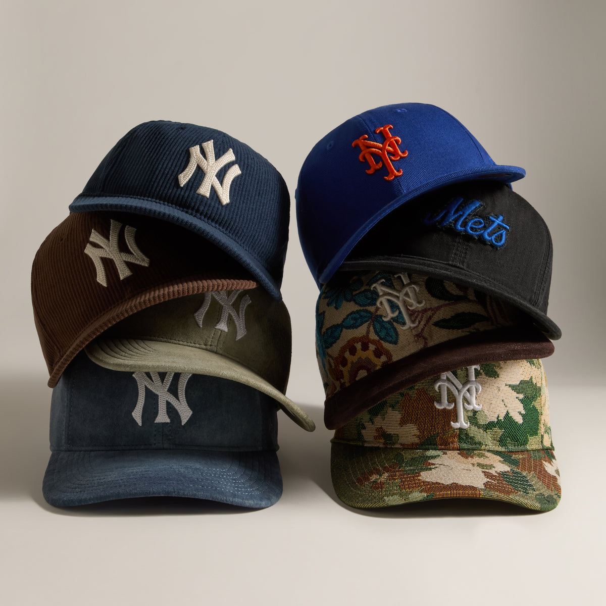 Stack of Kith and MLB baseball caps including navy Yankees and blue Mets snapbacks with camo accents