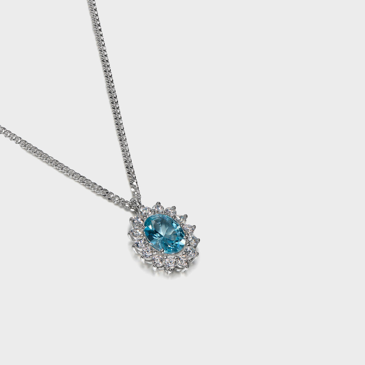 Hatton Labs Crown Stone Pendant Necklace in topaz, angled view of blue oval stone with white halo on silver curb chain
