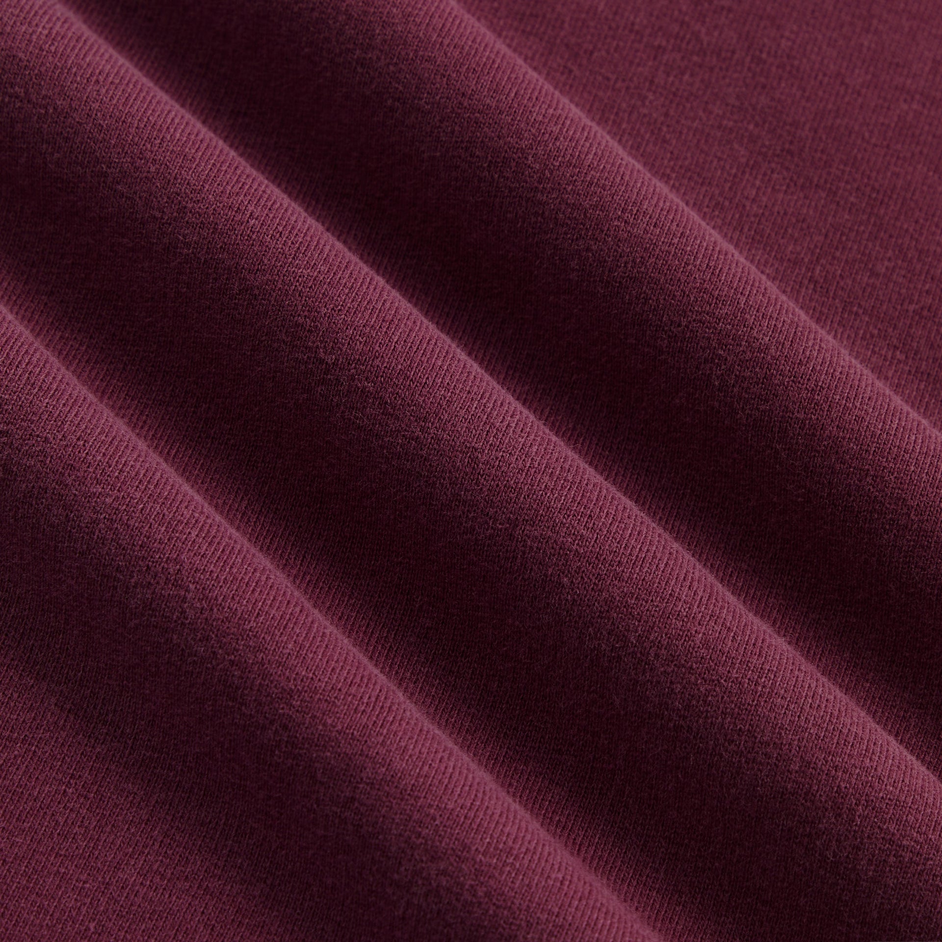 Close-up of soft burgundy Essence fleece fabric texture of Kith Baby Logo Nelson Short