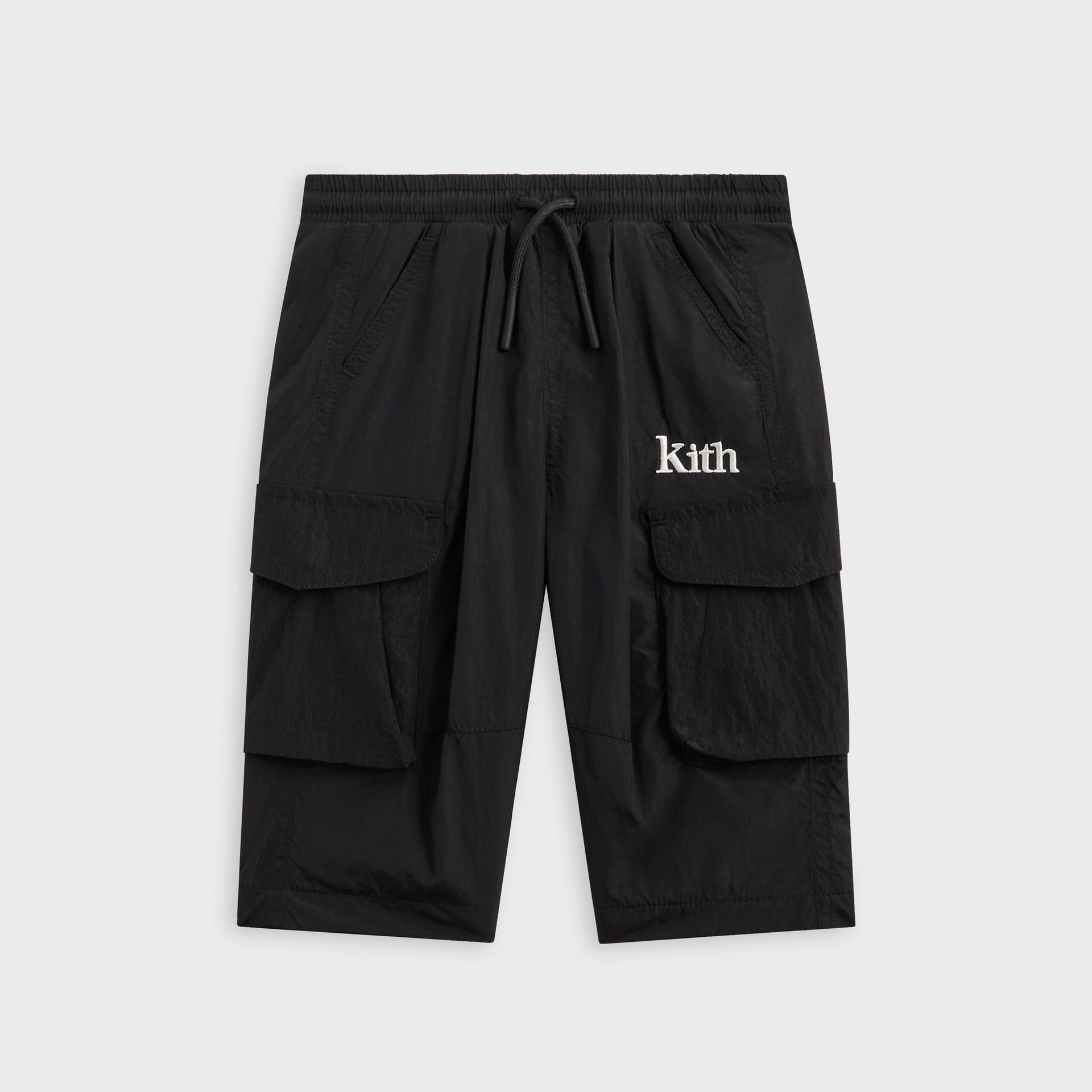 Kith Baby Parachute Pant in black, front view of nylon cargo shorts with drawstring waist, flap pockets and white Kith logo