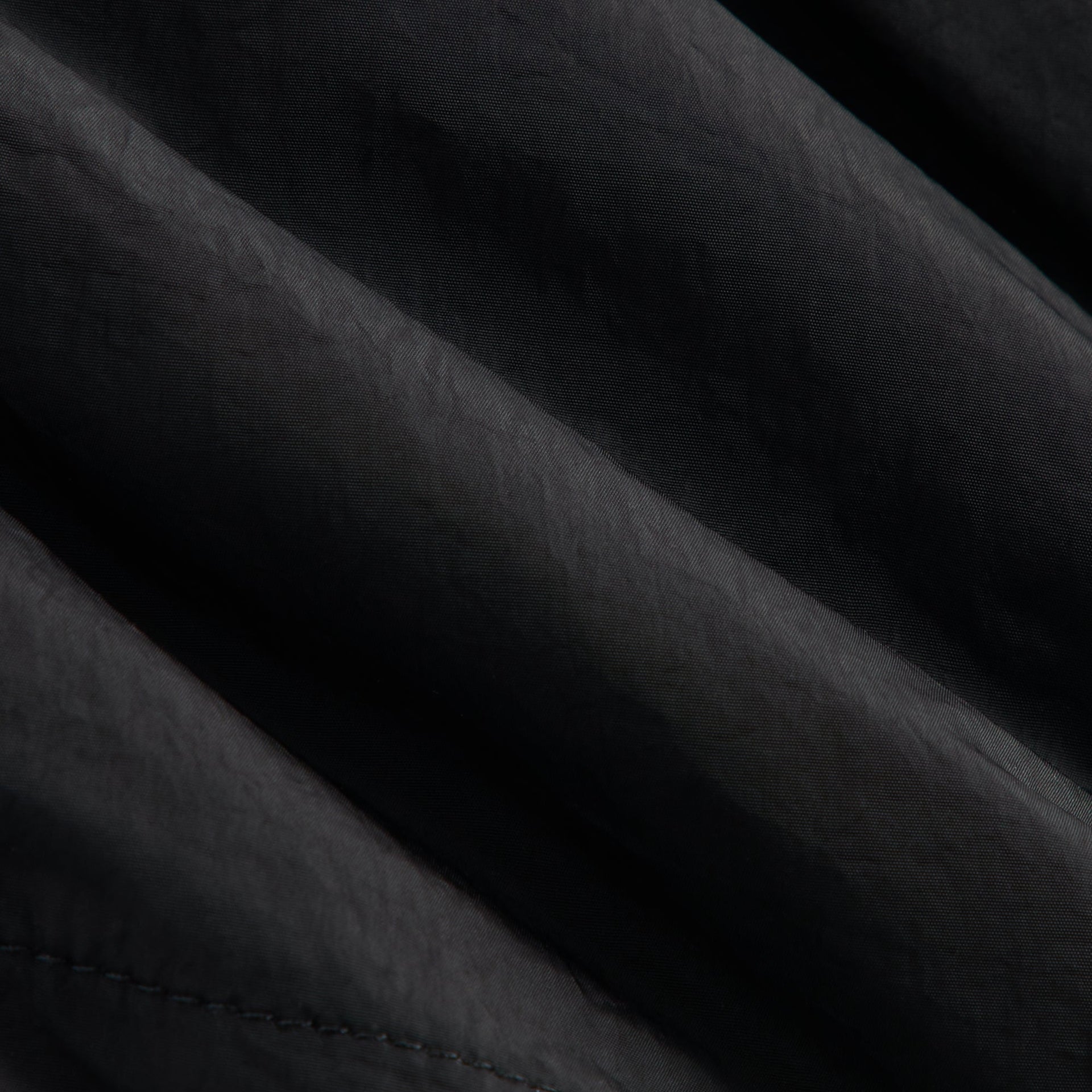 Close-up of black crinkled nylon fabric and topstitching on Kith Baby Parachute Pant