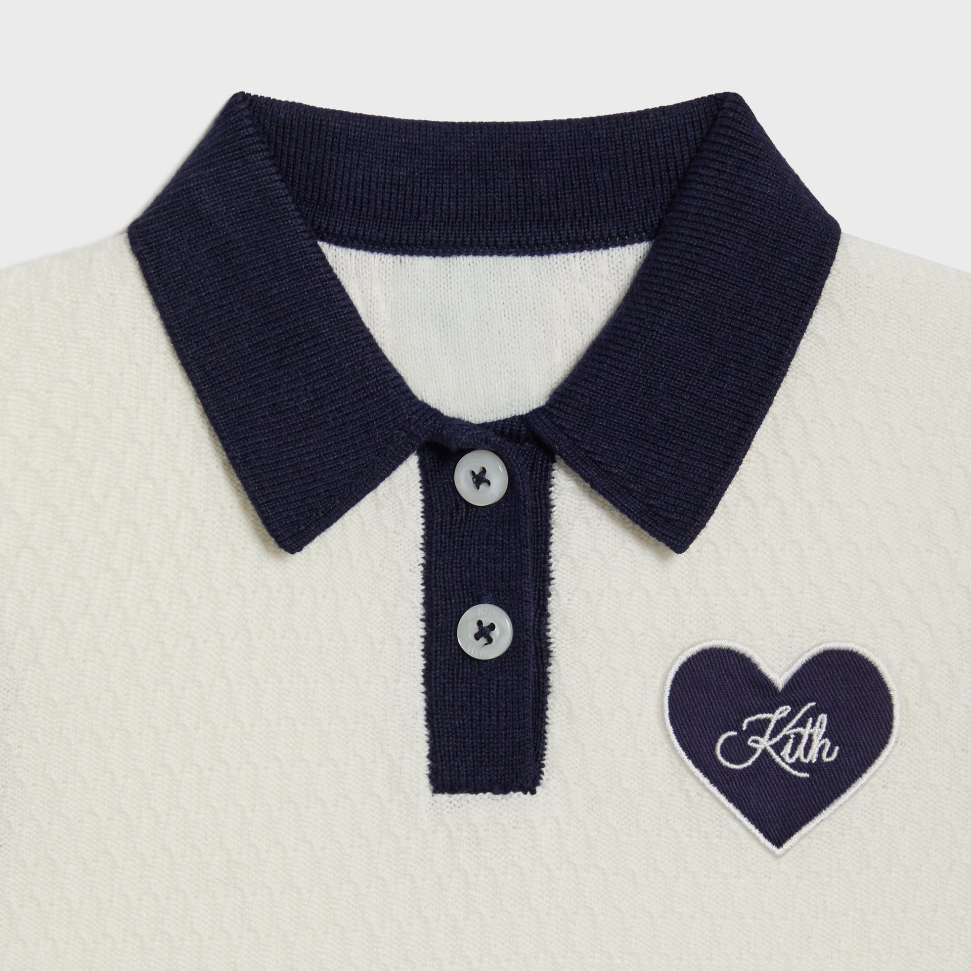Kith Baby Knit Teagan Polo Dress, close-up of navy collar, two-button placket and embroidered Kith heart patch