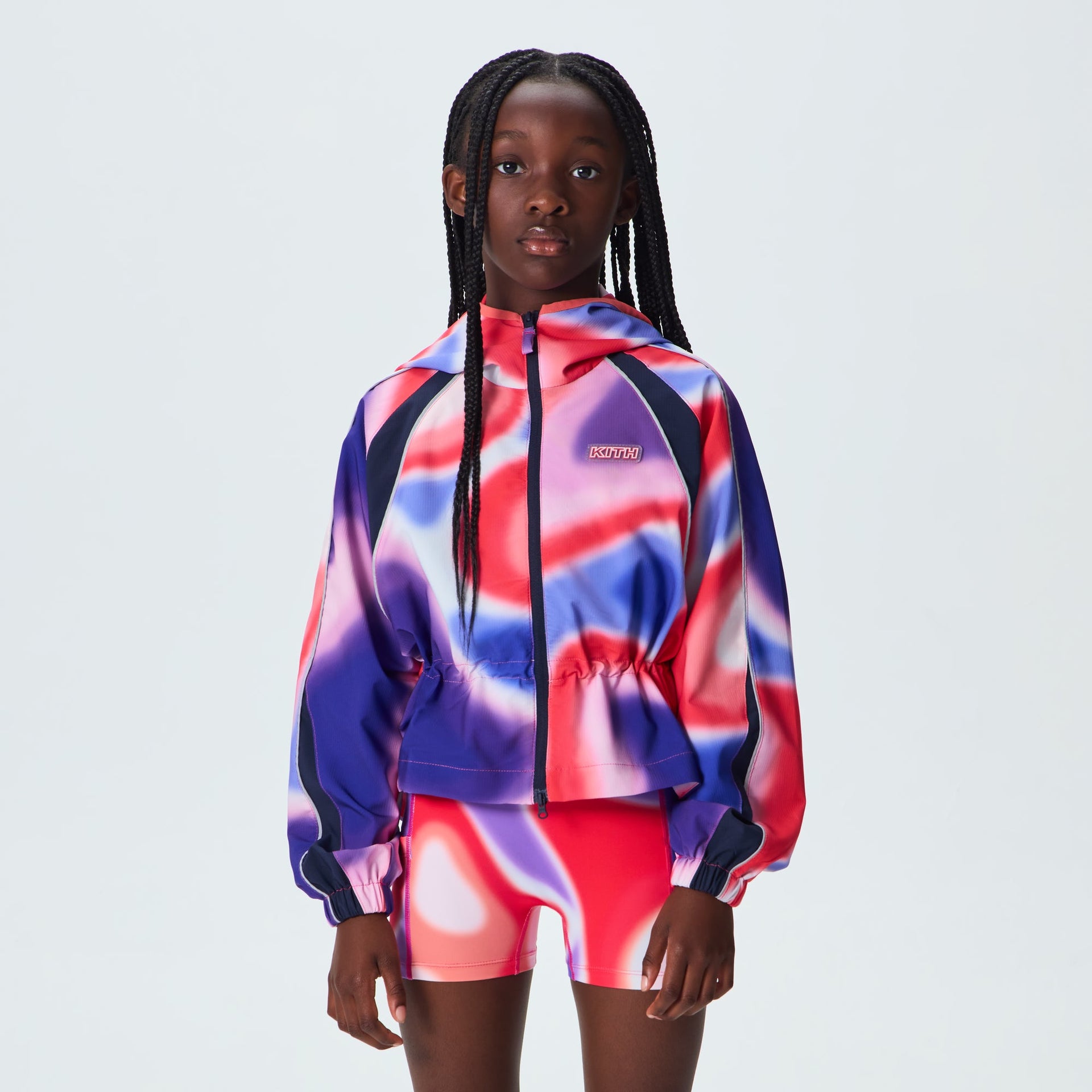 Kith Kids Lora Windbreaker in Tempo print worn on model, front view with cinched waist over matching bike shorts