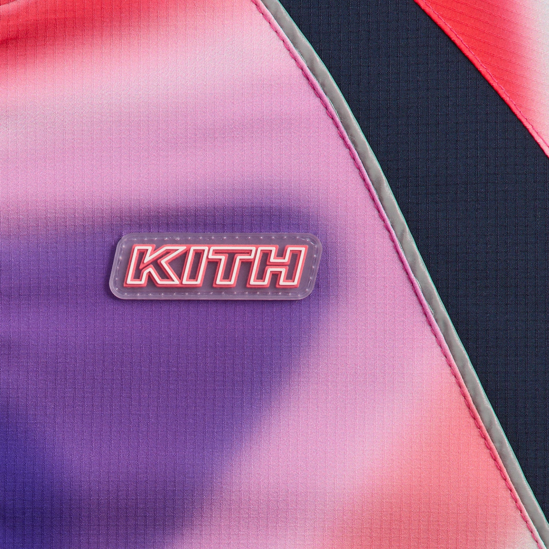 Kith Kids Lora Windbreaker close-up of rubberized KITH chest patch on pink and purple swirl fabric with navy panel