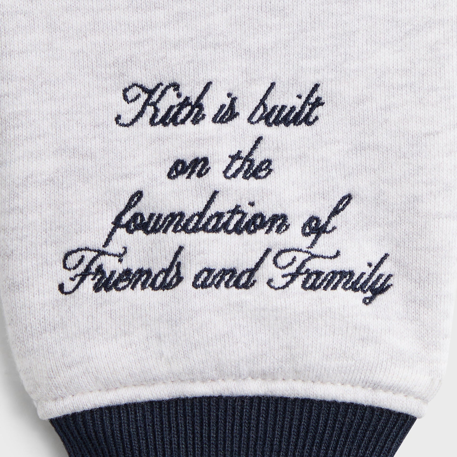 Kith Kids Wyona Fleece Bomber Jacket, close-up of sleeve embroidery reading Kith is built on the foundation of Friends and Family