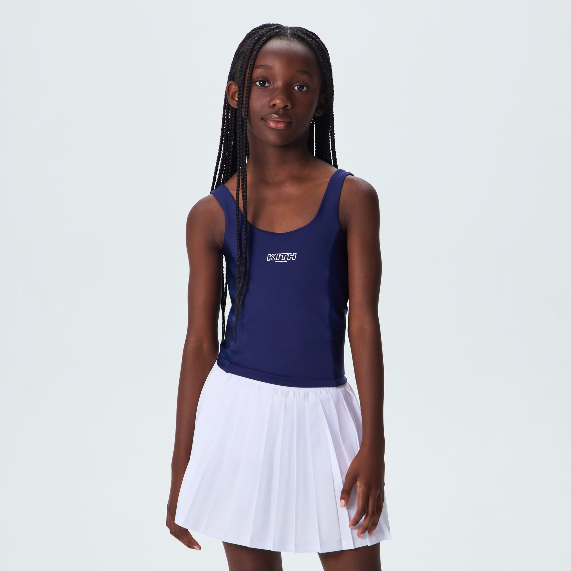 Young girl wearing Kith Kids Active Zamira Tank in Nocturnal navy with white pleated skirt, on-model front view