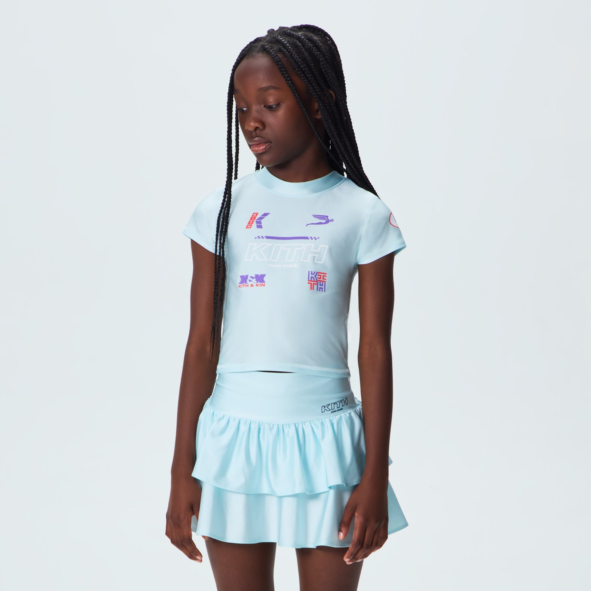Kith Kids Active Mulberry Logo Tee in light blue worn by child with matching ruffle skirt, front view