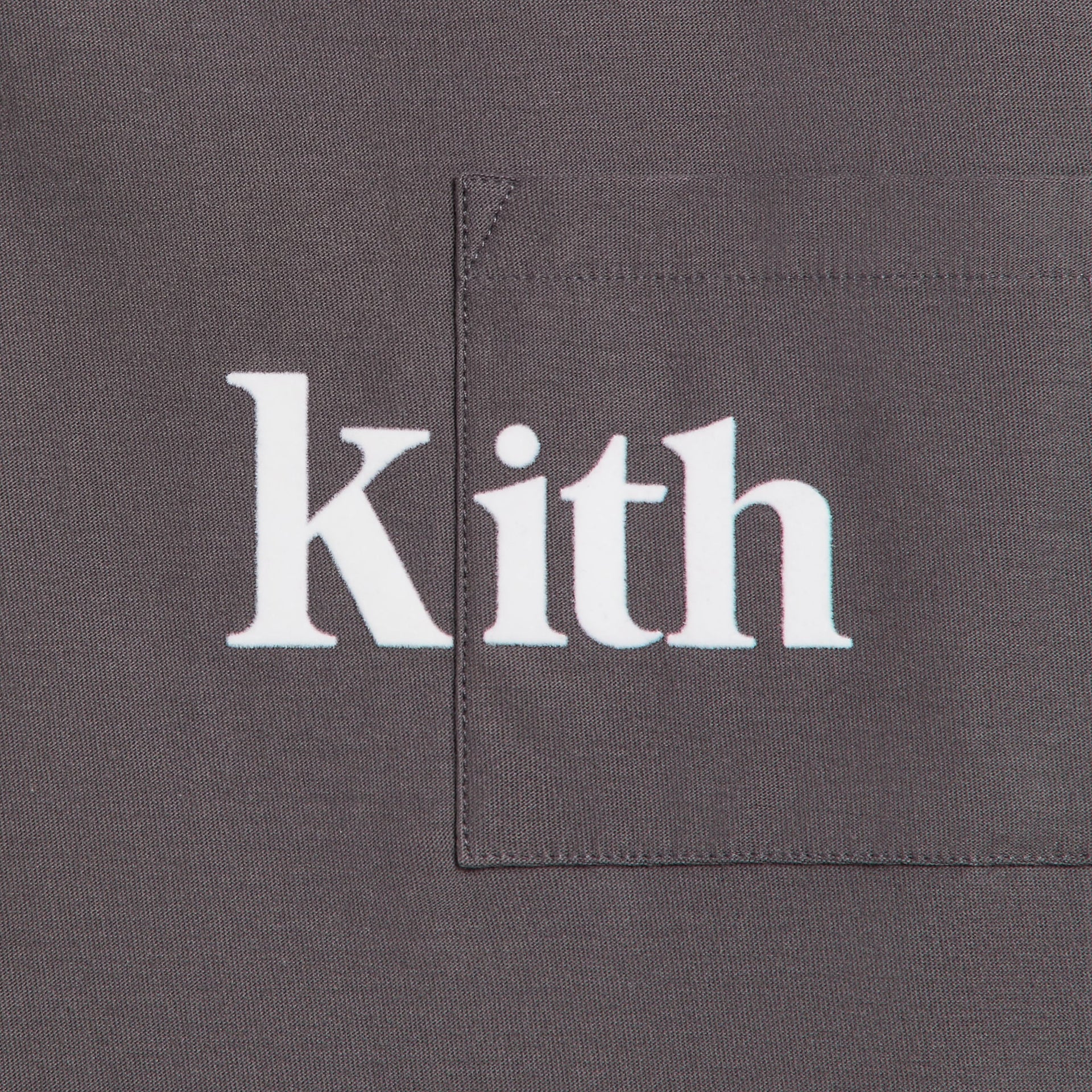 Kith Kids Quinn II Tee close-up of chest pocket with white Kith serif logo on charcoal