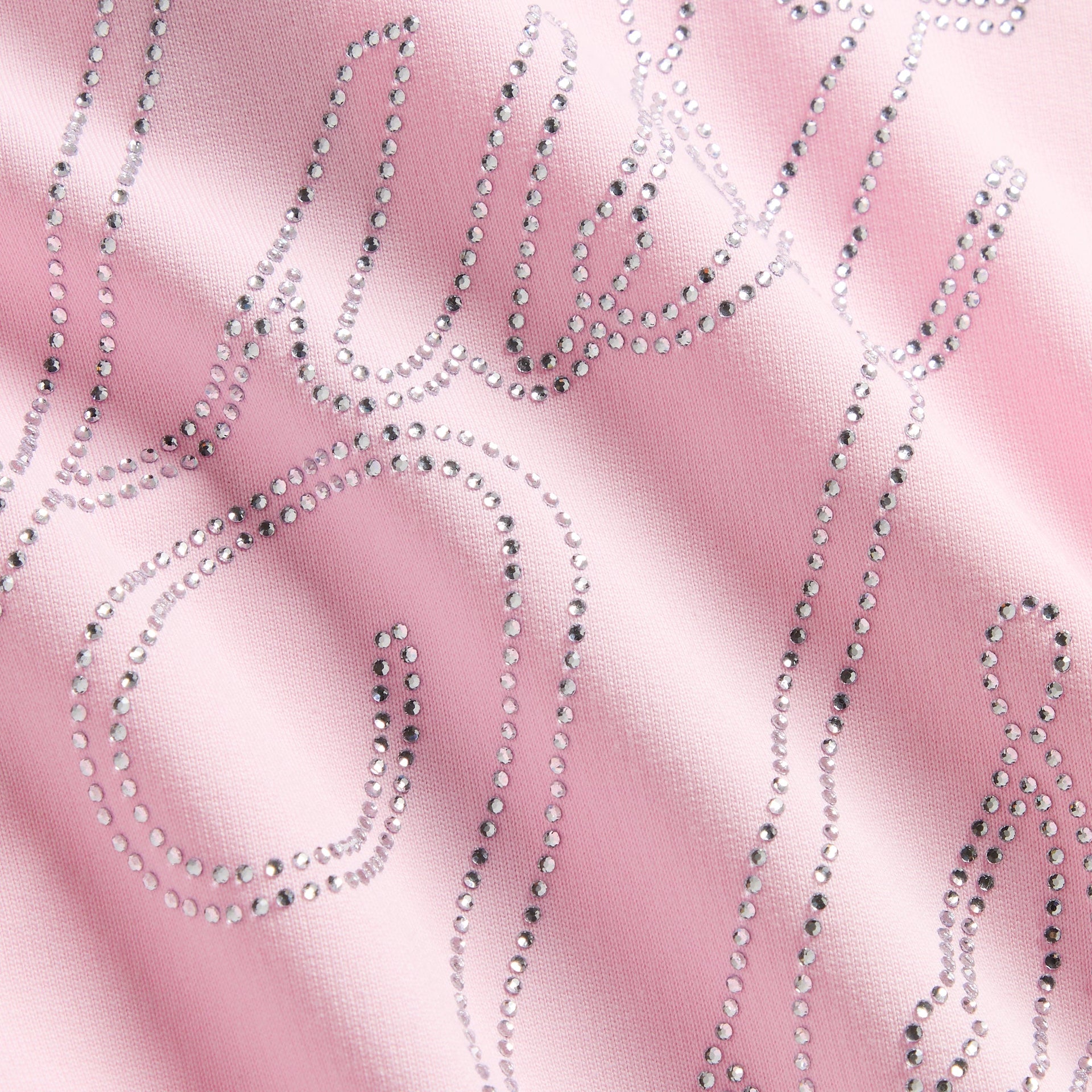 Macro close-up of silver rhinestone script studs on pink Bloom fabric of Cropped Nelson Hoodie