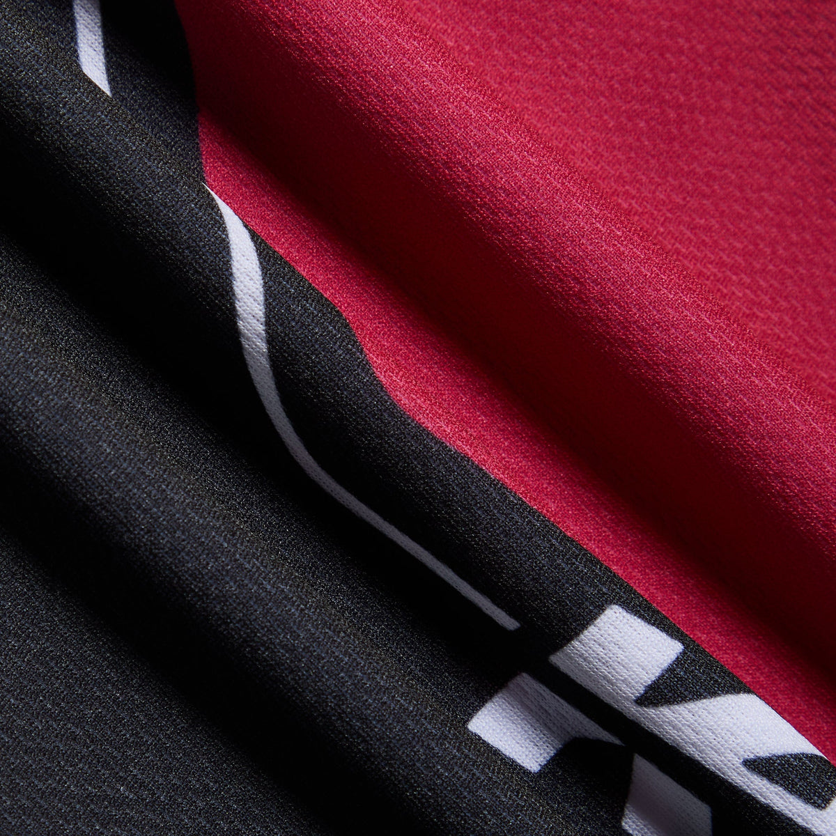Close-up of the black and red mesh fabric of the Kith Kids Moto Mesh Donovan jersey tee