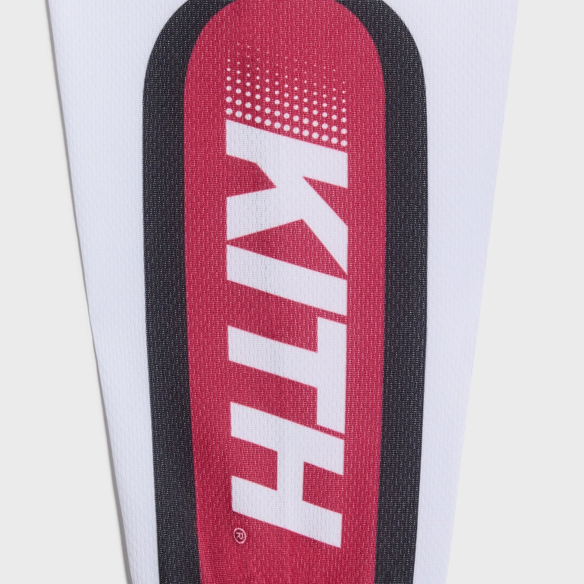 Close-up of the Kith Kids Moto jersey sleeve with vertical white KITH logo on a red panel with halftone fade