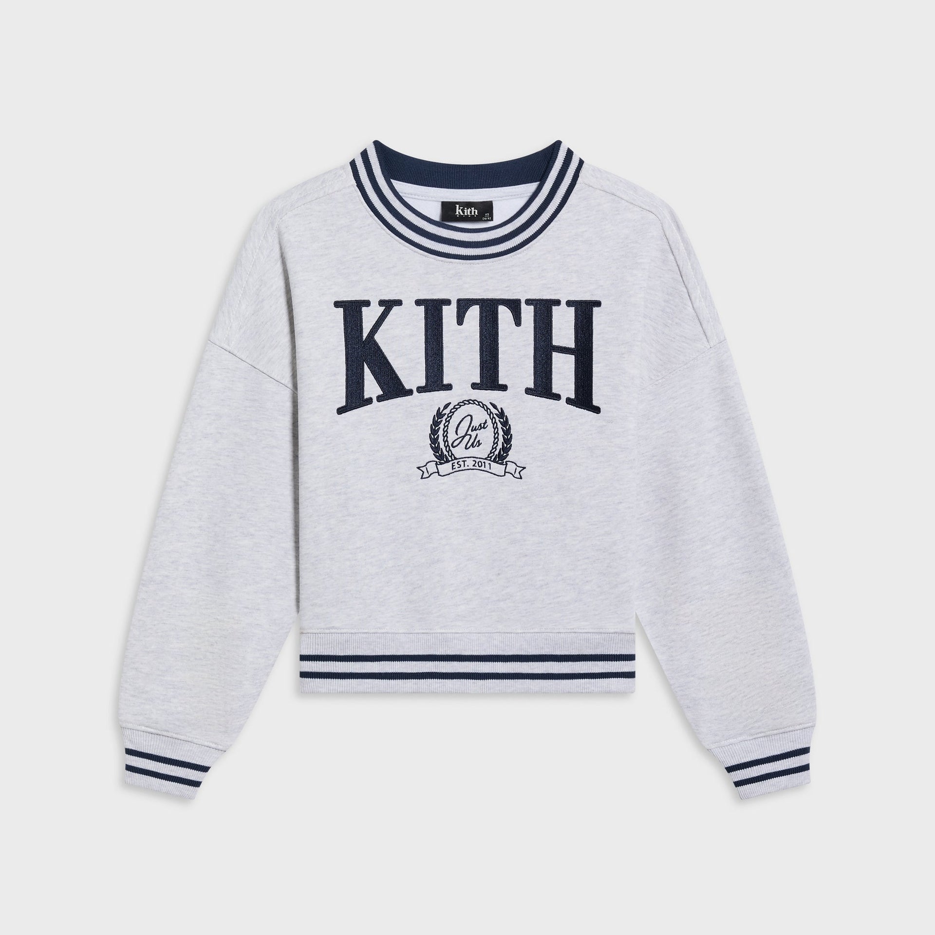 Kith Kids Collegiate Nelson crewneck in light heather grey, flat lay with navy striped ribbing and embroidered KITH crest logo