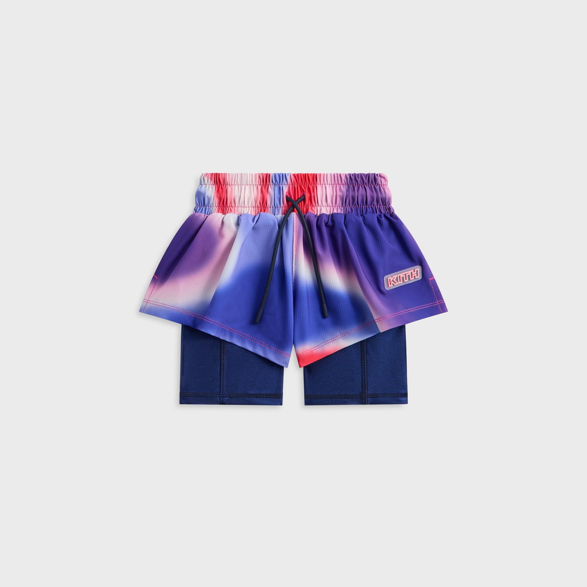 Kith Kids Printed Jazmyn II Active Short in blurred purple, blue and red print, front flat lay of layered short over navy liner with KITH patch