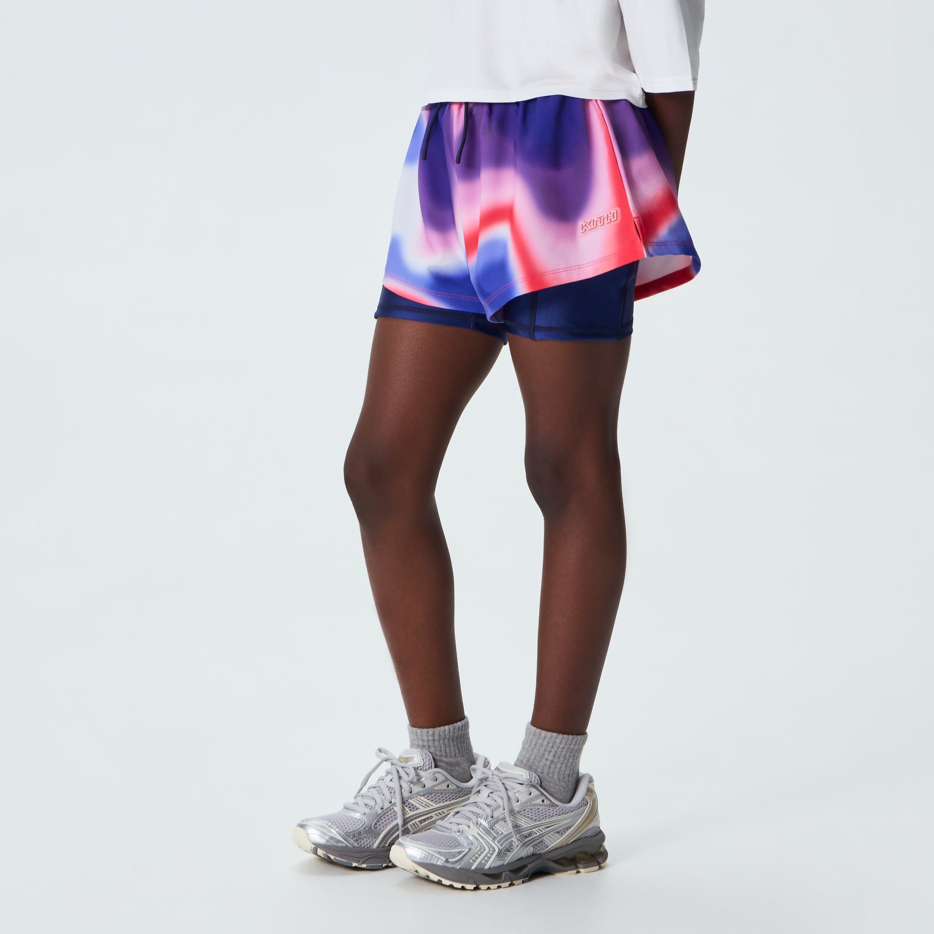 Kith Kids Printed Jazmyn II Active Short, on-model back three-quarter view showing flowy printed layer over navy compression liner