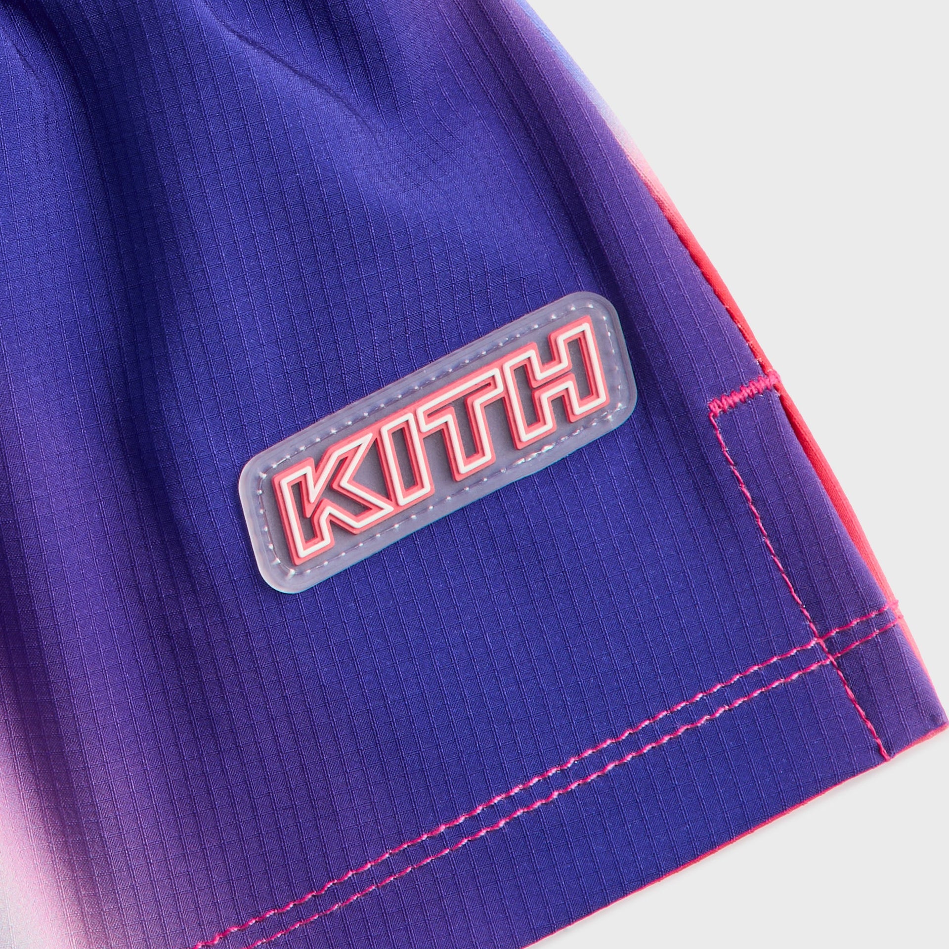 Kith Kids Printed Jazmyn II Active Short, close-up of rubber KITH logo patch on purple printed hem