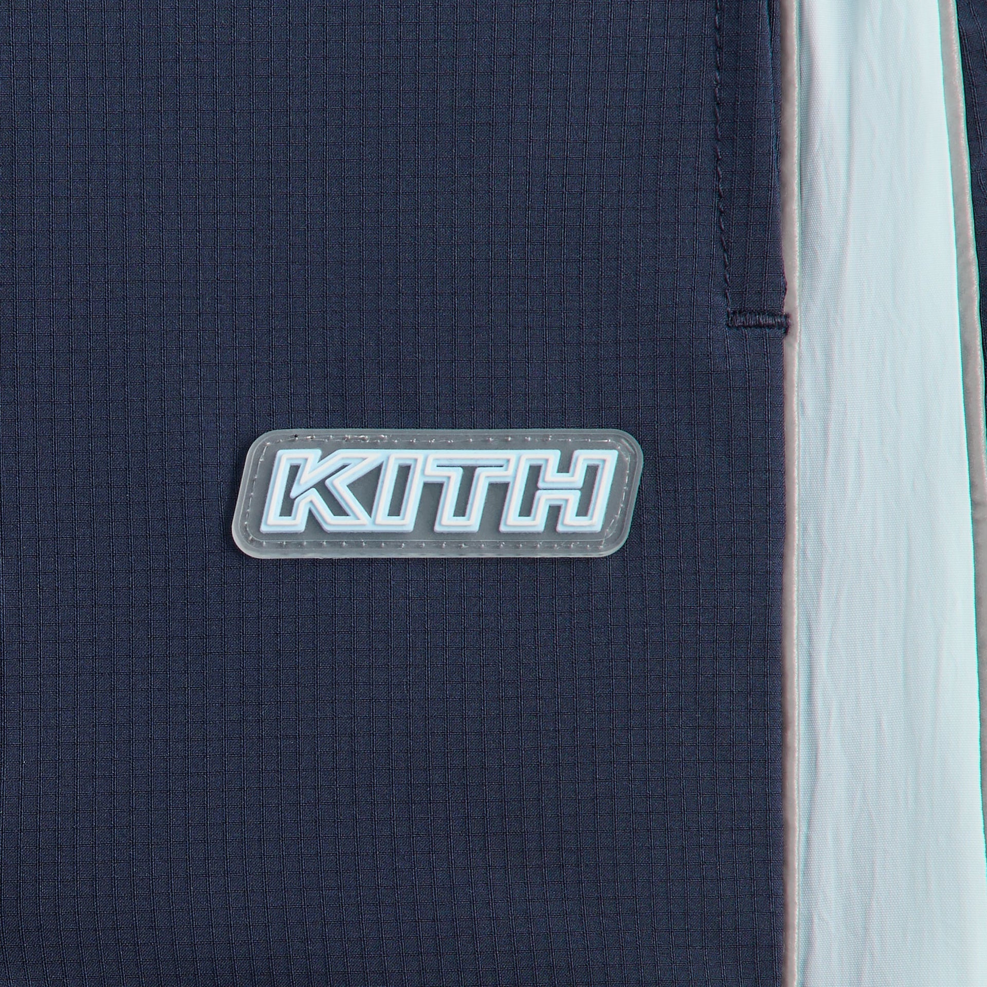 Kith Kids Lora Track Pant, close-up of KITH rubber patch on navy ripstop beside light blue side stripe