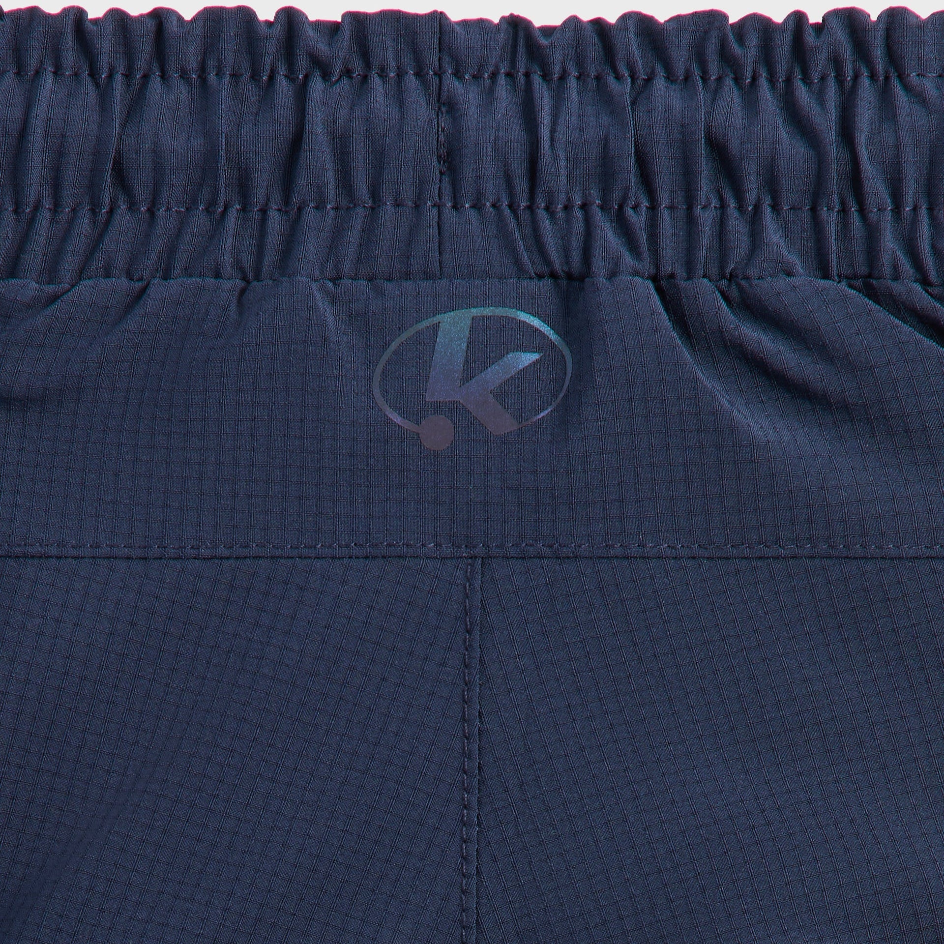 Kith Kids Lora Track Pant, close-up of elastic waistband with tonal Kith K oval logo on navy fabric