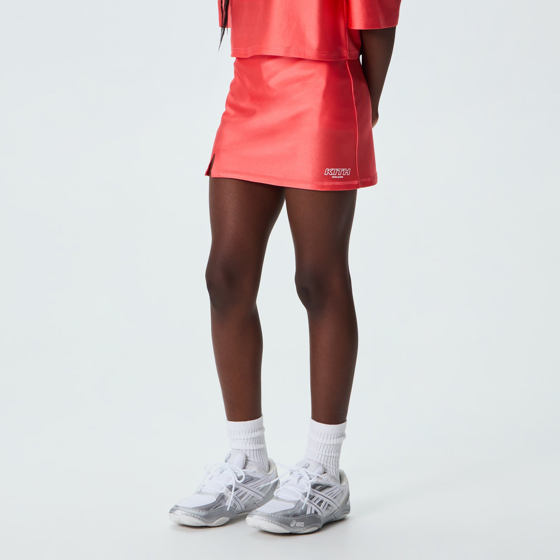 Kith Kids Active Ari Skort in carnation coral worn on model, back side view with matching top and sneakers