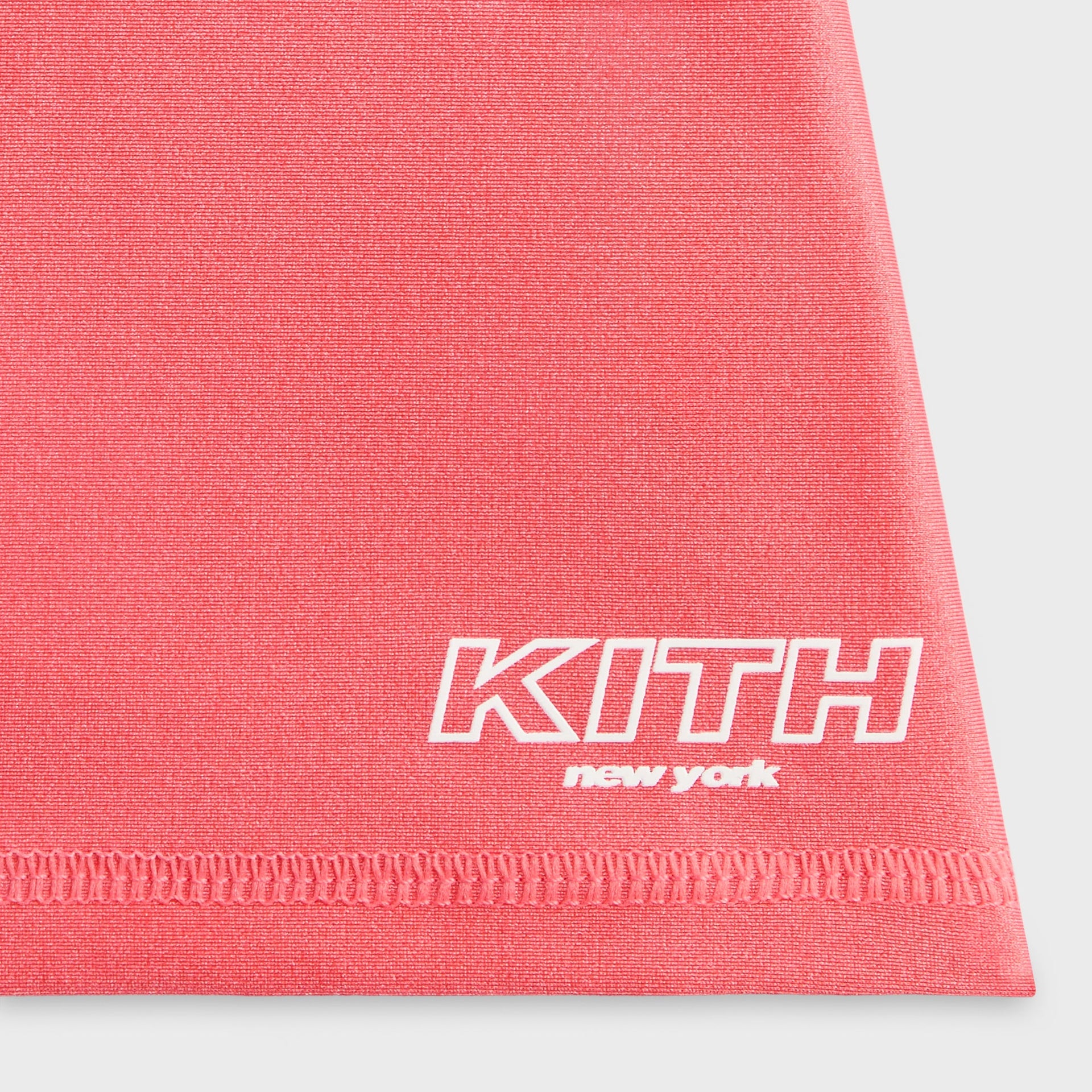 Kith Kids Active Ari Skort in carnation coral, close-up of KITH New York logo and stitched hem