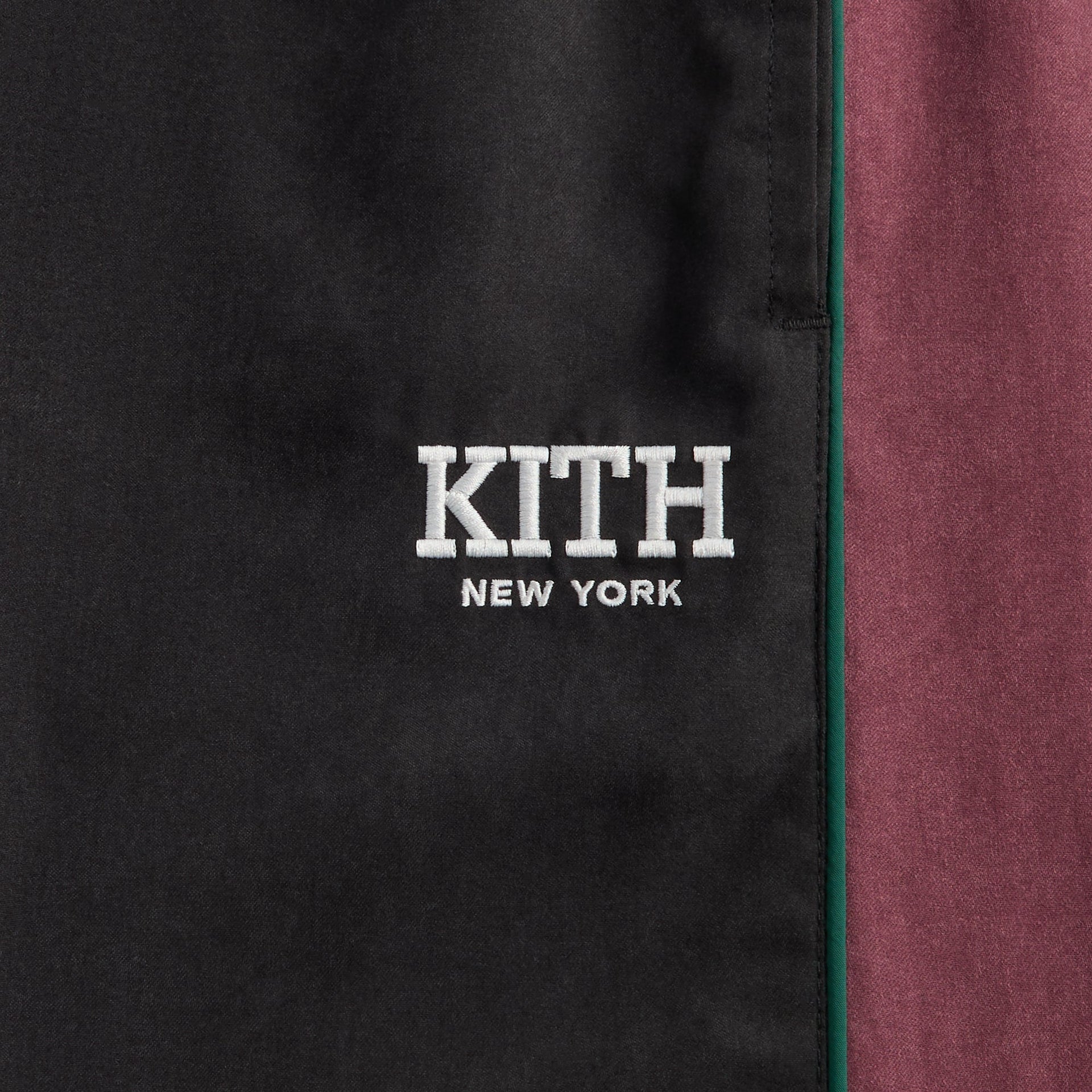 Kith Kids Milo II Track Pant in black, close-up of white KITH New York logo with green piping